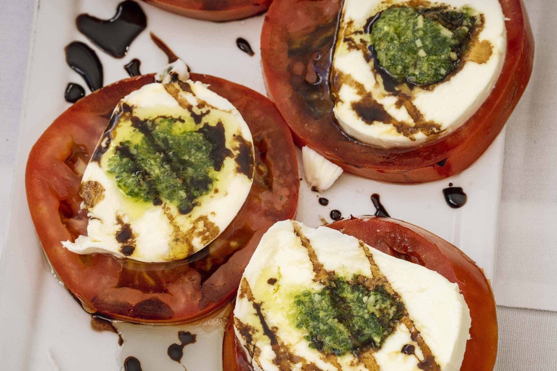 A white plate topped with sliced tomatoes and mozzarella.