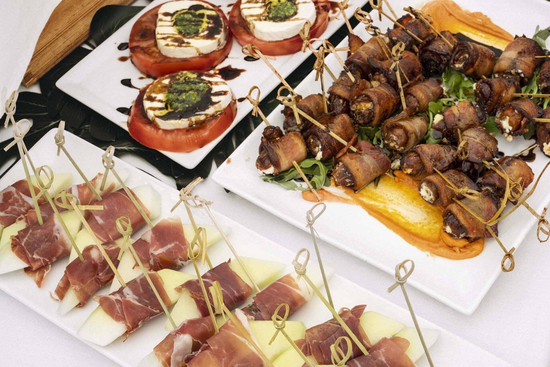 A table topped with plates of food including bacon wrapped dates