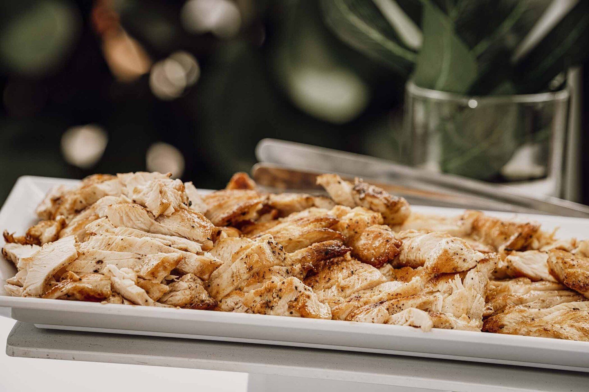 A white plate topped with shredded chicken is sitting on a table.