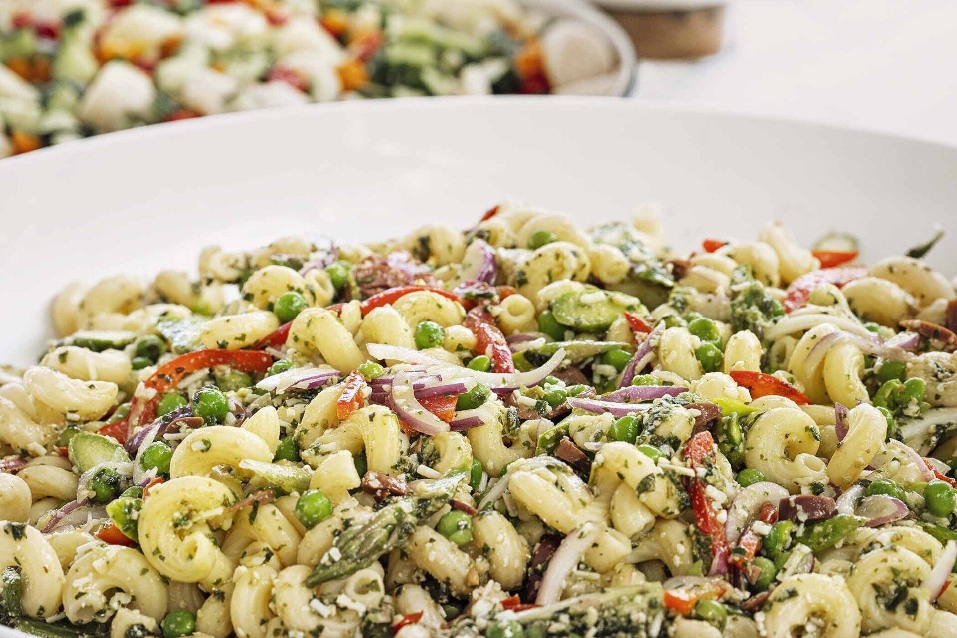 A close up of a pasta salad with vegetables on a plate.