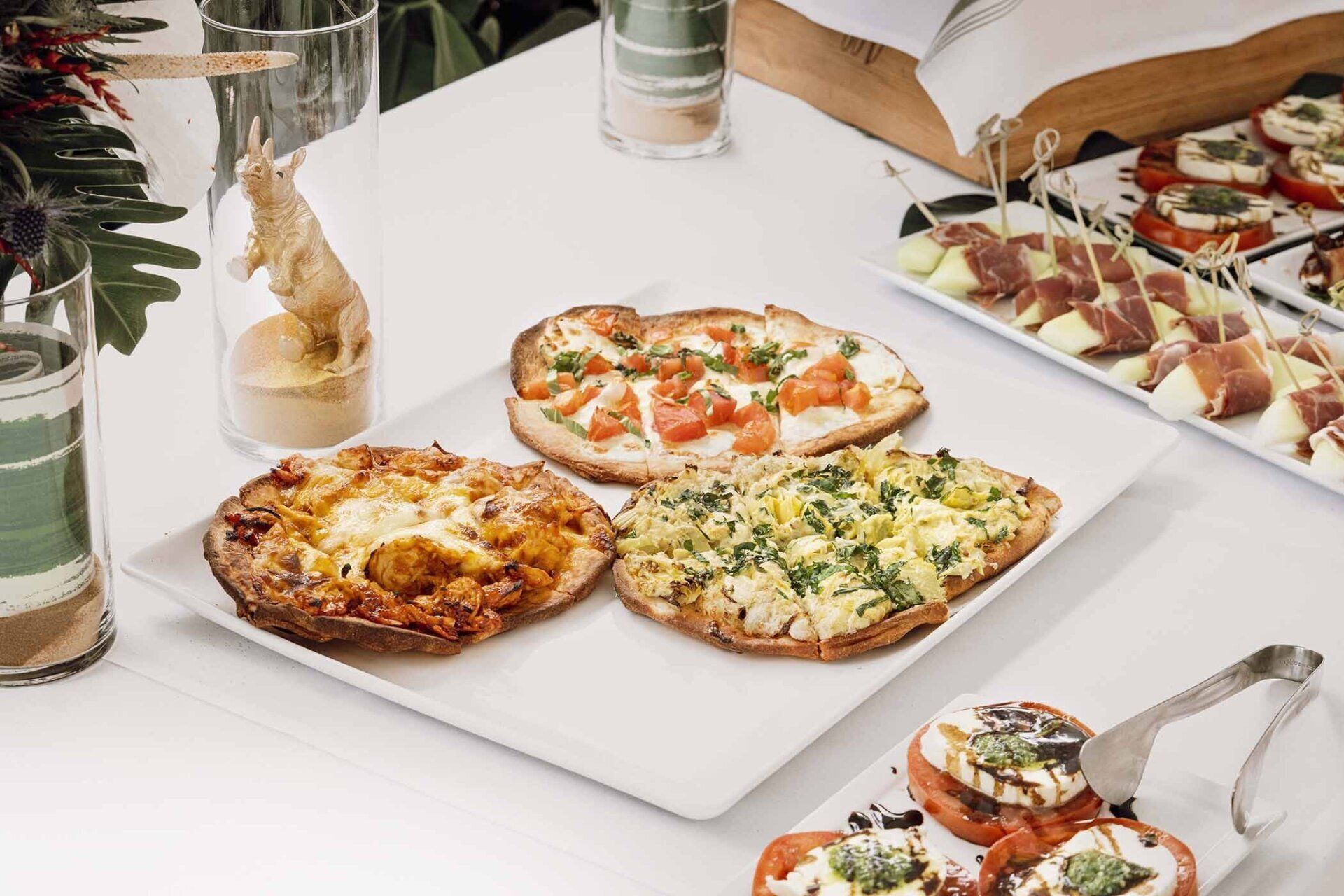 A table topped with plates of pizza and appetizers.