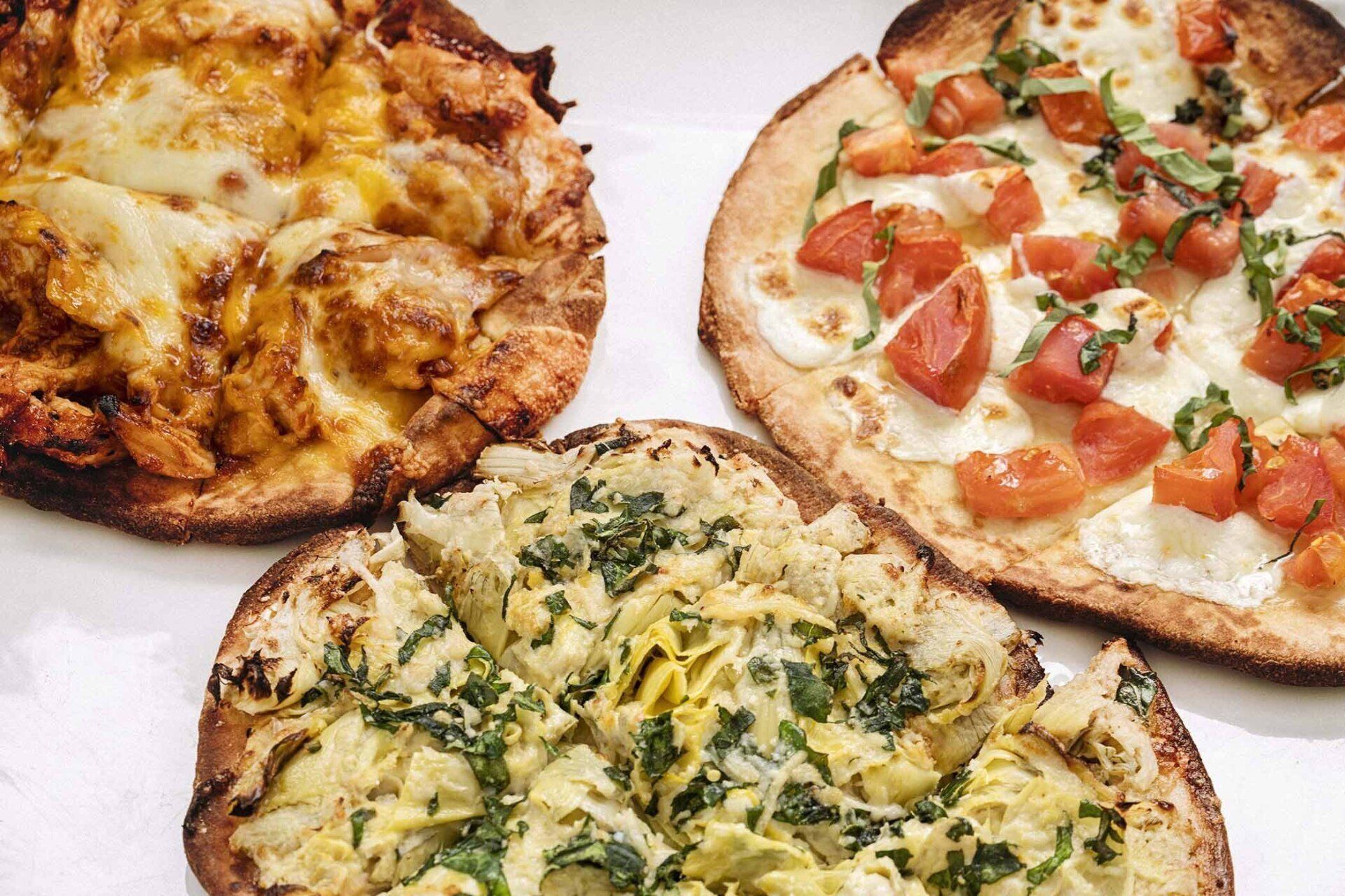 Three different types of pizzas are sitting on a table.