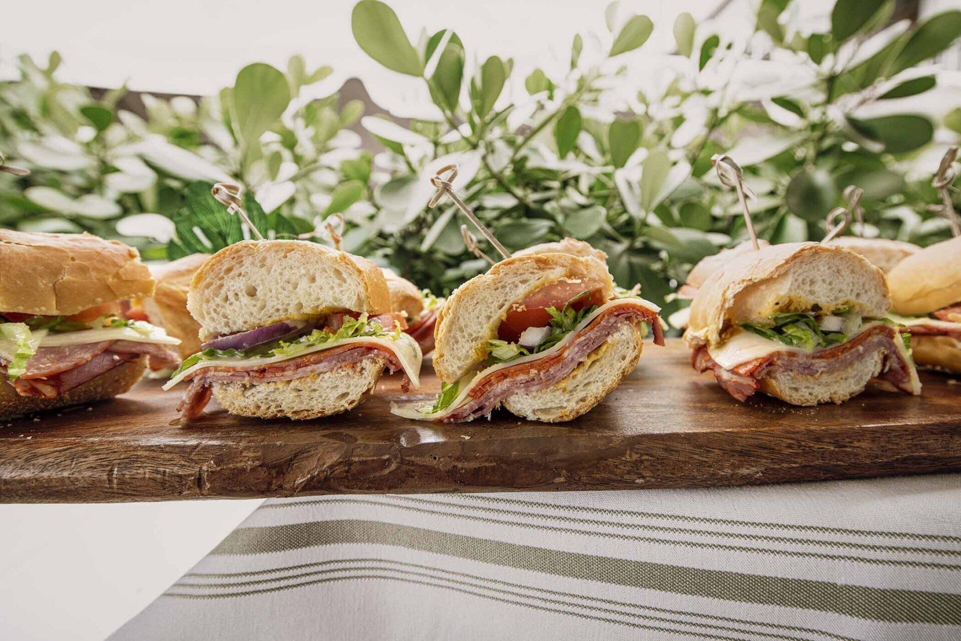 A row of sandwiches sitting on top of a wooden cutting board.