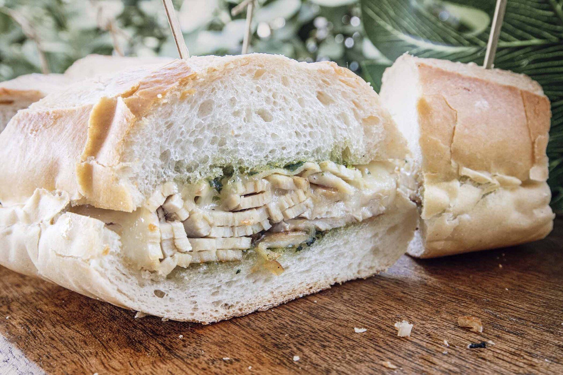 A sandwich is cut in half on a wooden table.