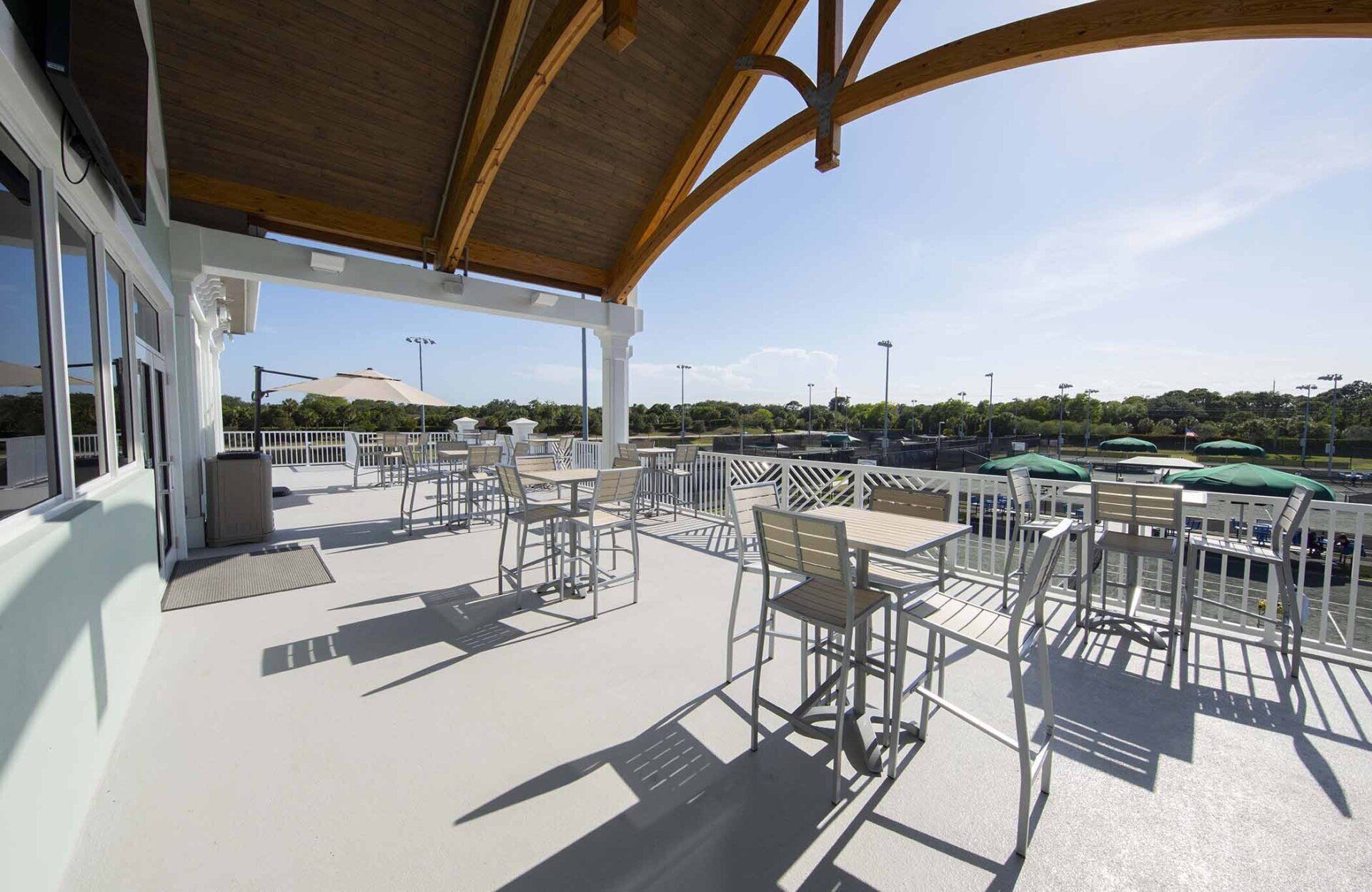 A patio with tables and chairs under a canopy overlooking a body of water.