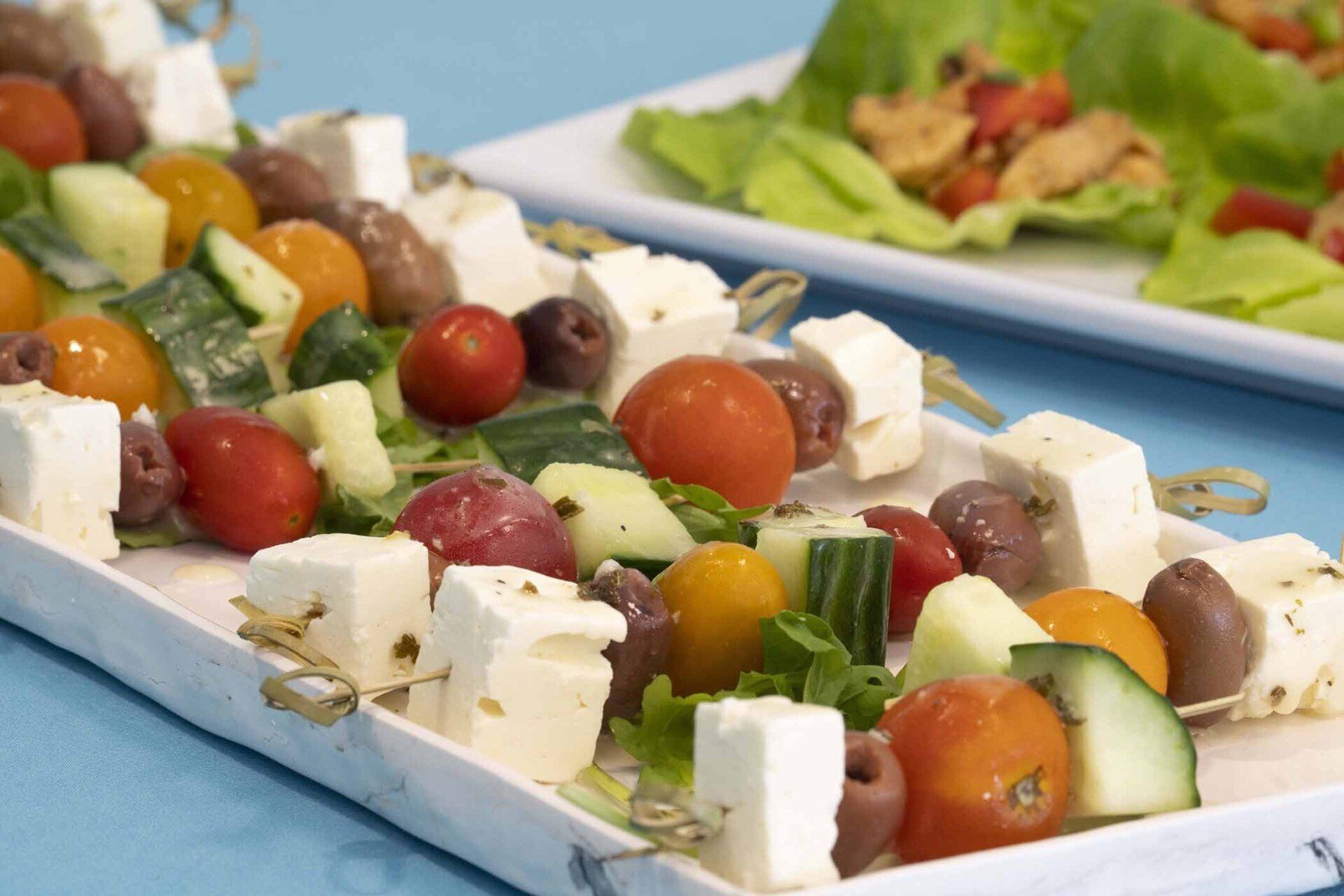 A white plate topped with tomatoes , cucumbers , olives and feta cheese.
