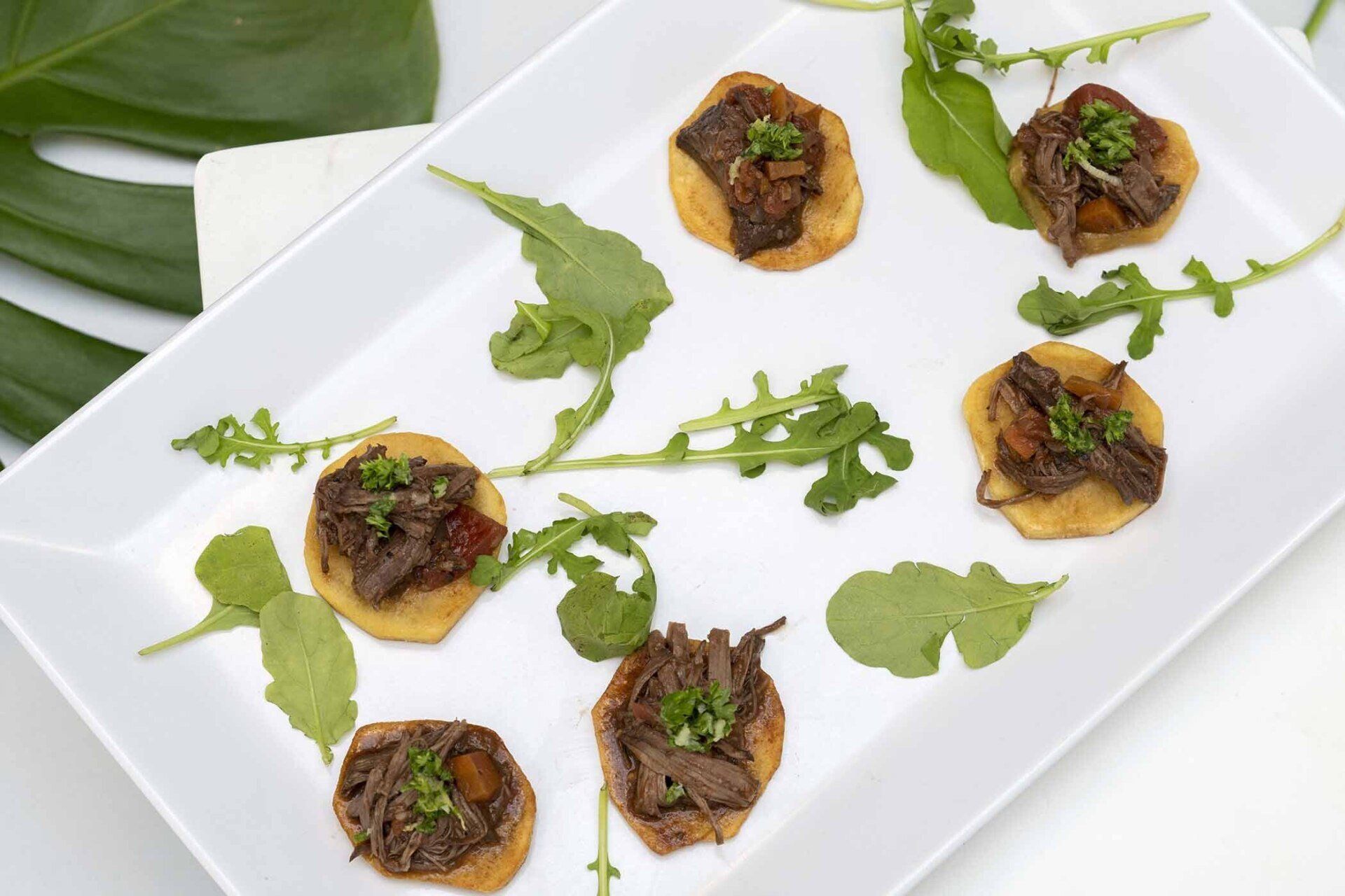 A white plate topped with small pieces of meat and vegetables
