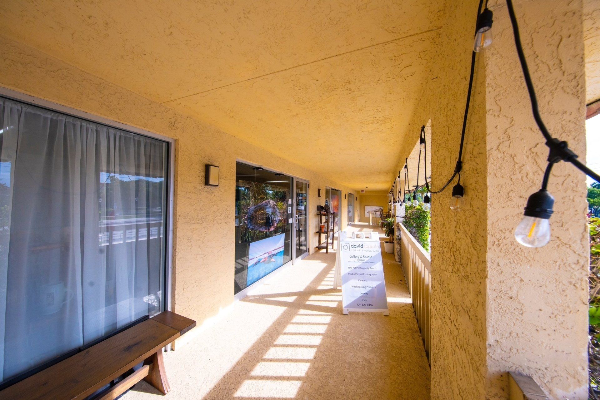 A long hallway between two buildings with a string of lights hanging from the ceiling.