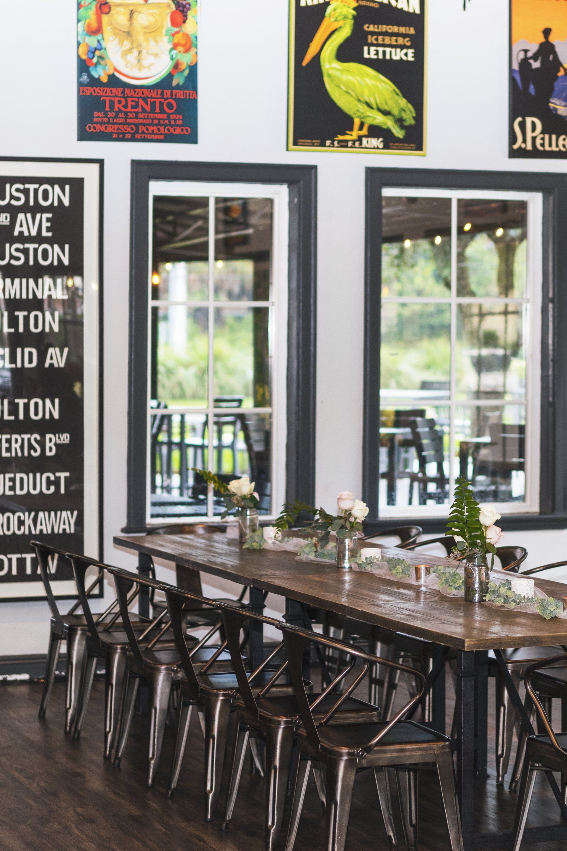 A dining room with a long table and chairs and posters on the wall.