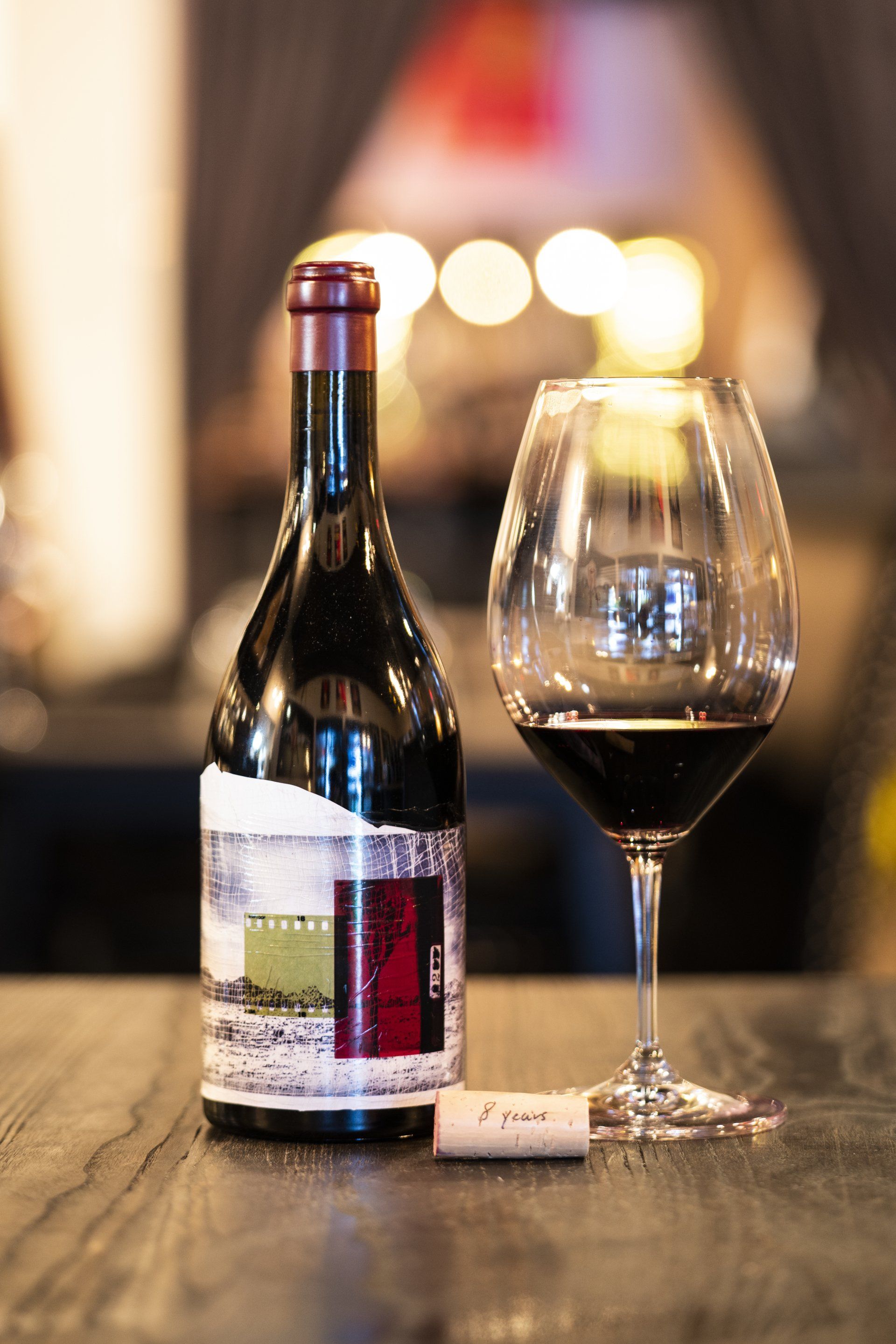 A bottle of wine and a glass of wine are on a table.