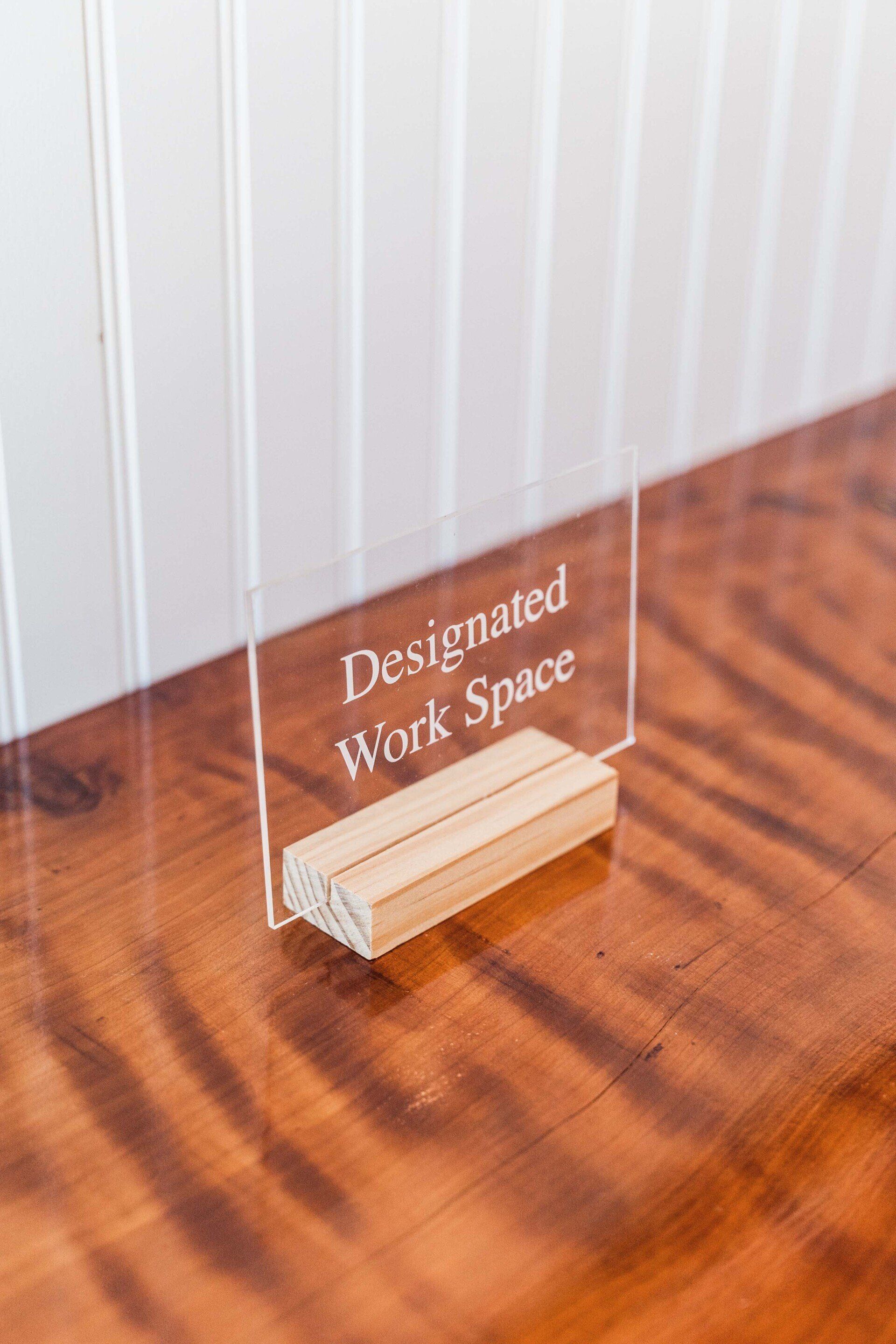 A sign on a wooden table that says designated work space.