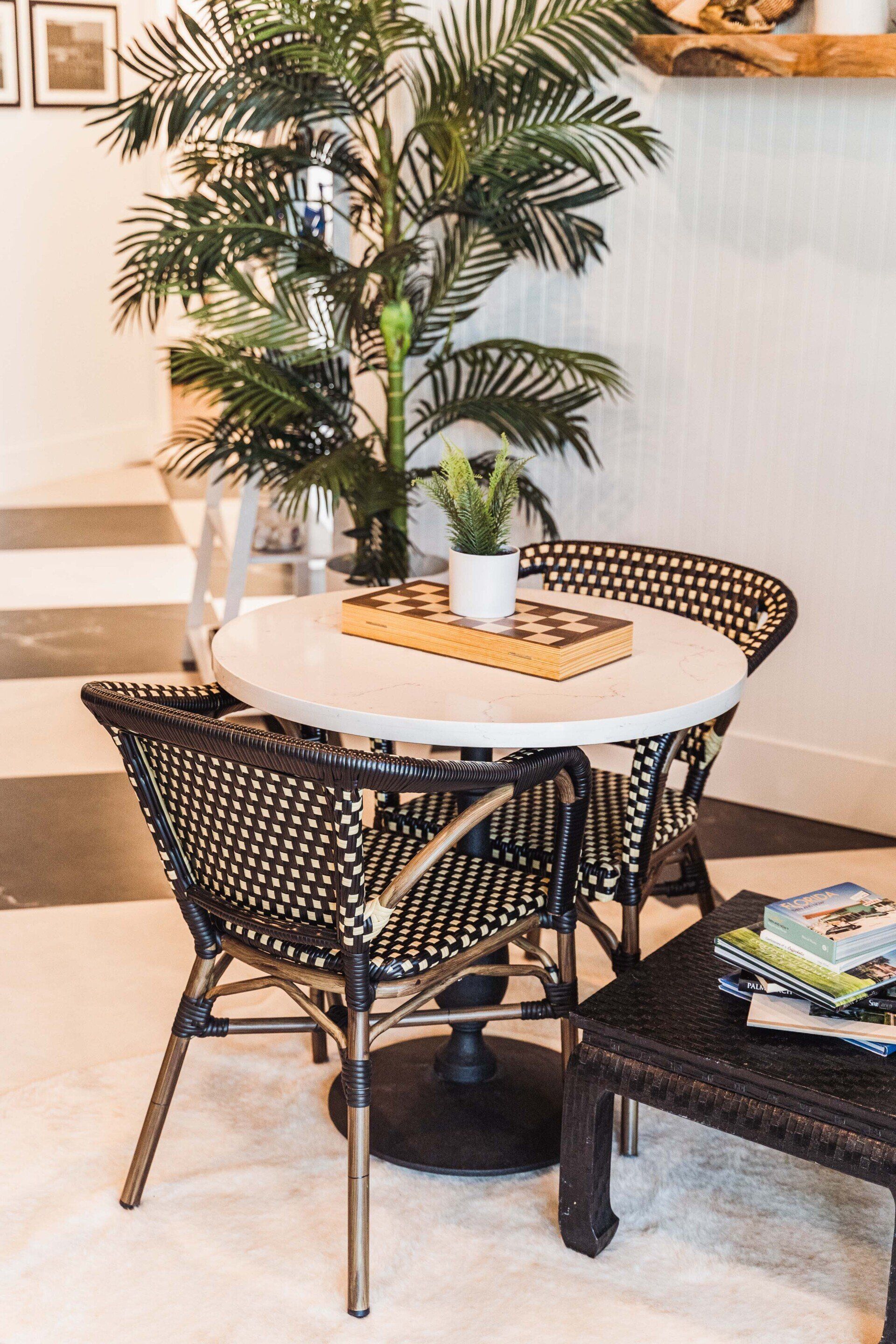 A living room with a table and chairs and a plant.