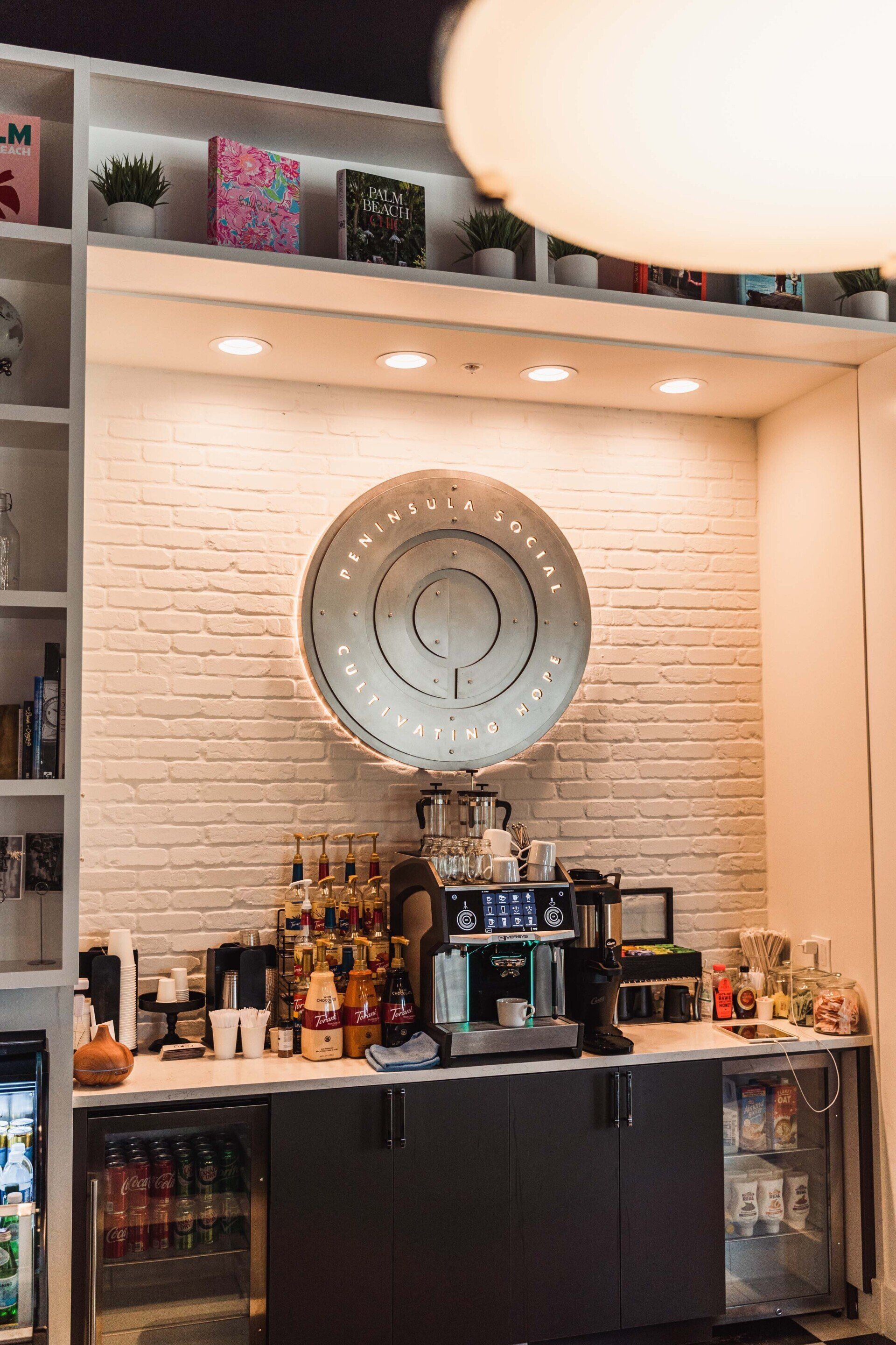 A bar with a clock on the wall and a brick wall behind it.