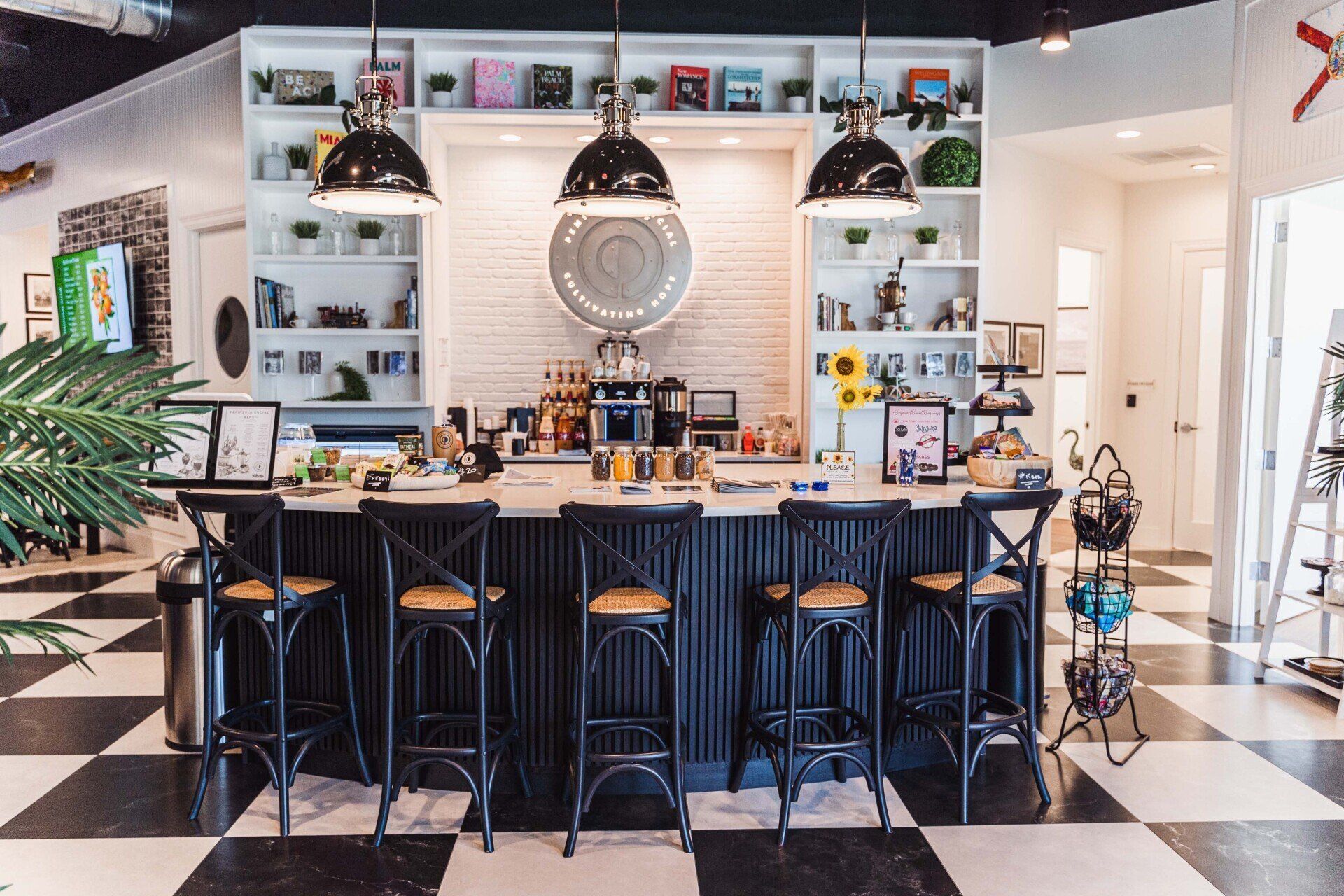 A kitchen with a long counter and stools and a checkered floor.
