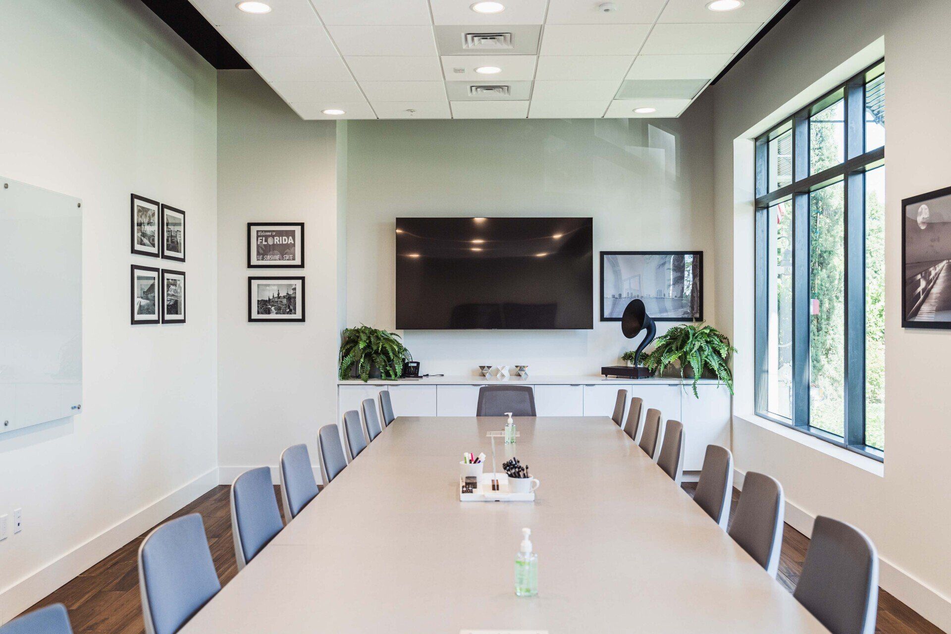 A conference room with a long table and chairs and a flat screen tv on the wall.