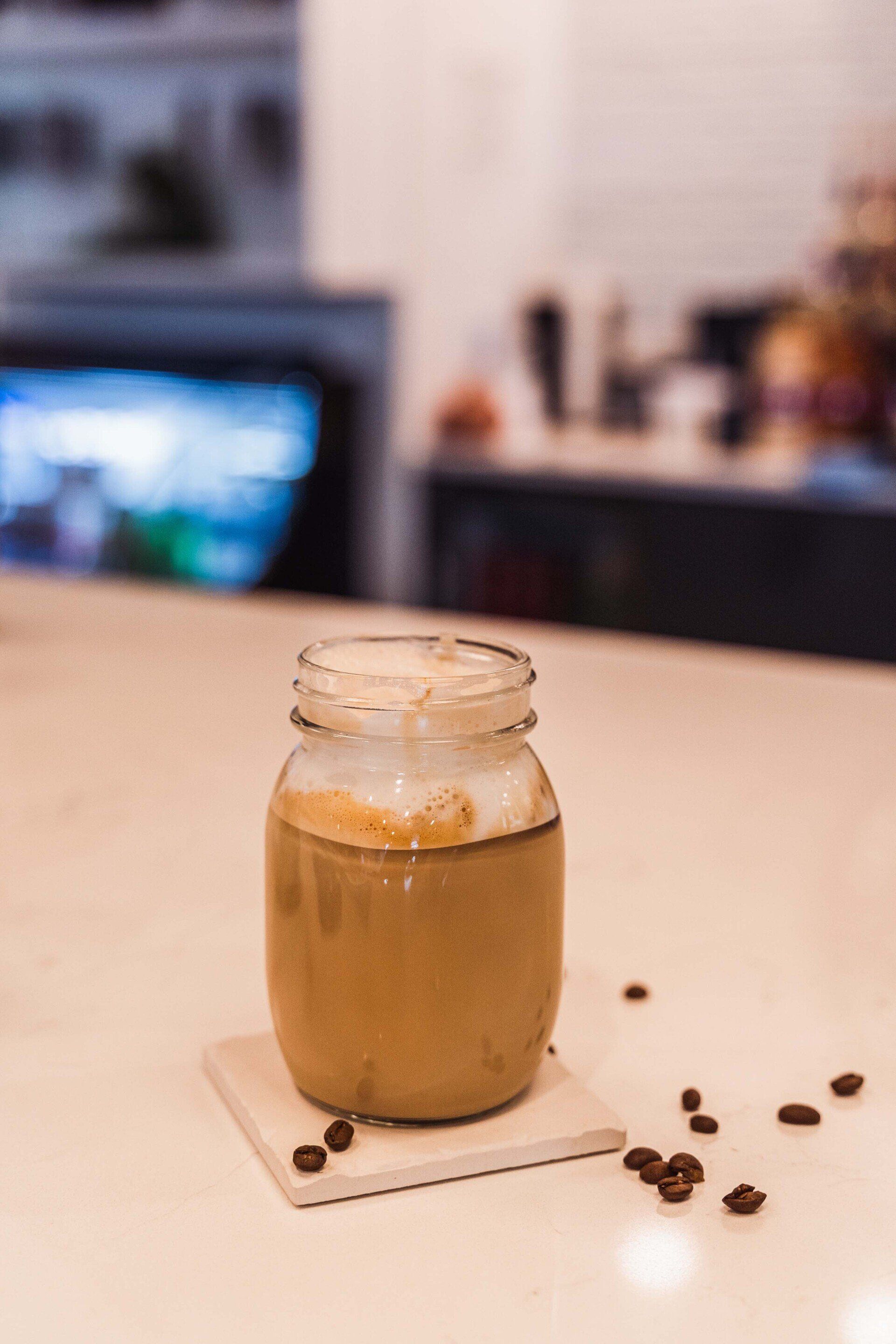A jar of coffee is sitting on a coaster on a counter.