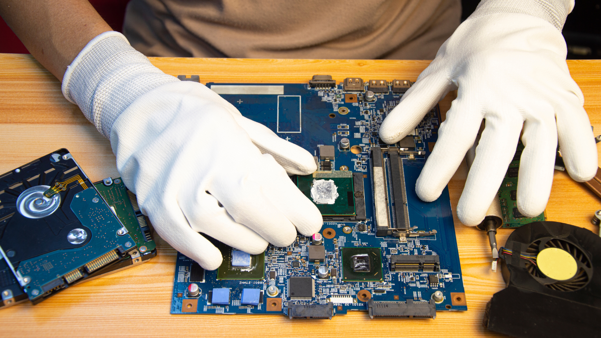 A person wearing white gloves is working on a motherboard.