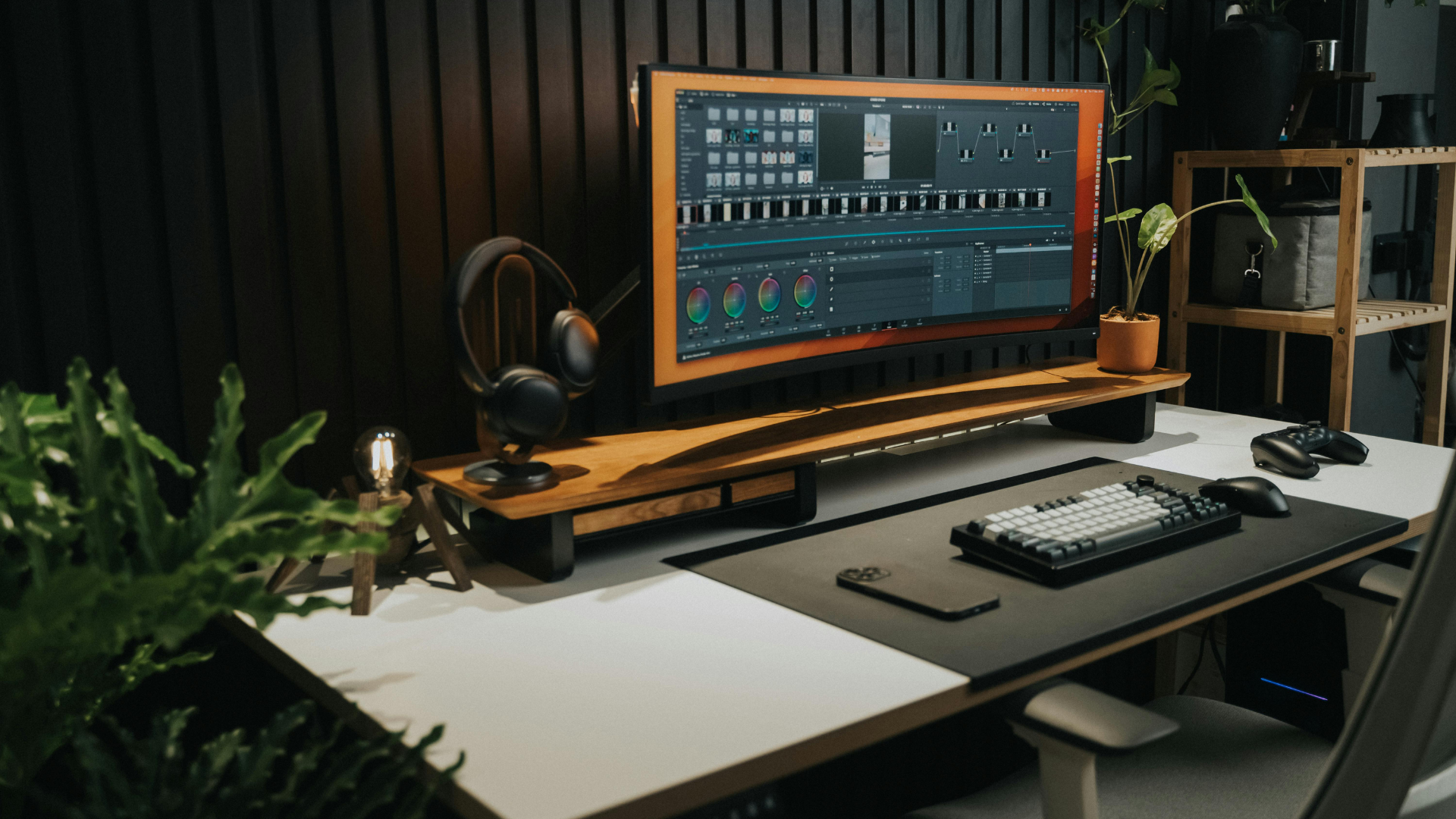 A computer desk with a monitor , keyboard , mouse and headphones on it.