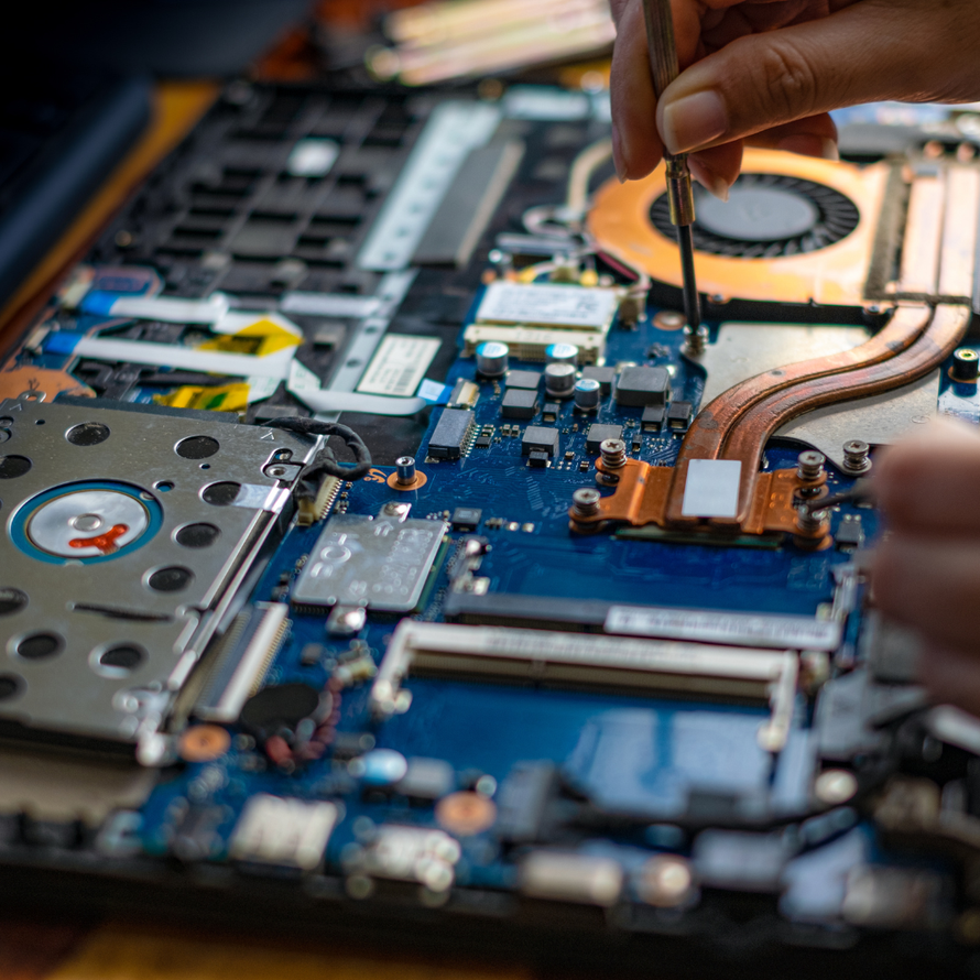 A person is fixing a laptop computer with a screwdriver.