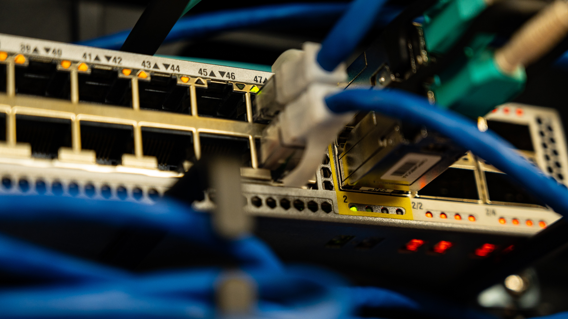 A bunch of wires are connected to a server in a server room.