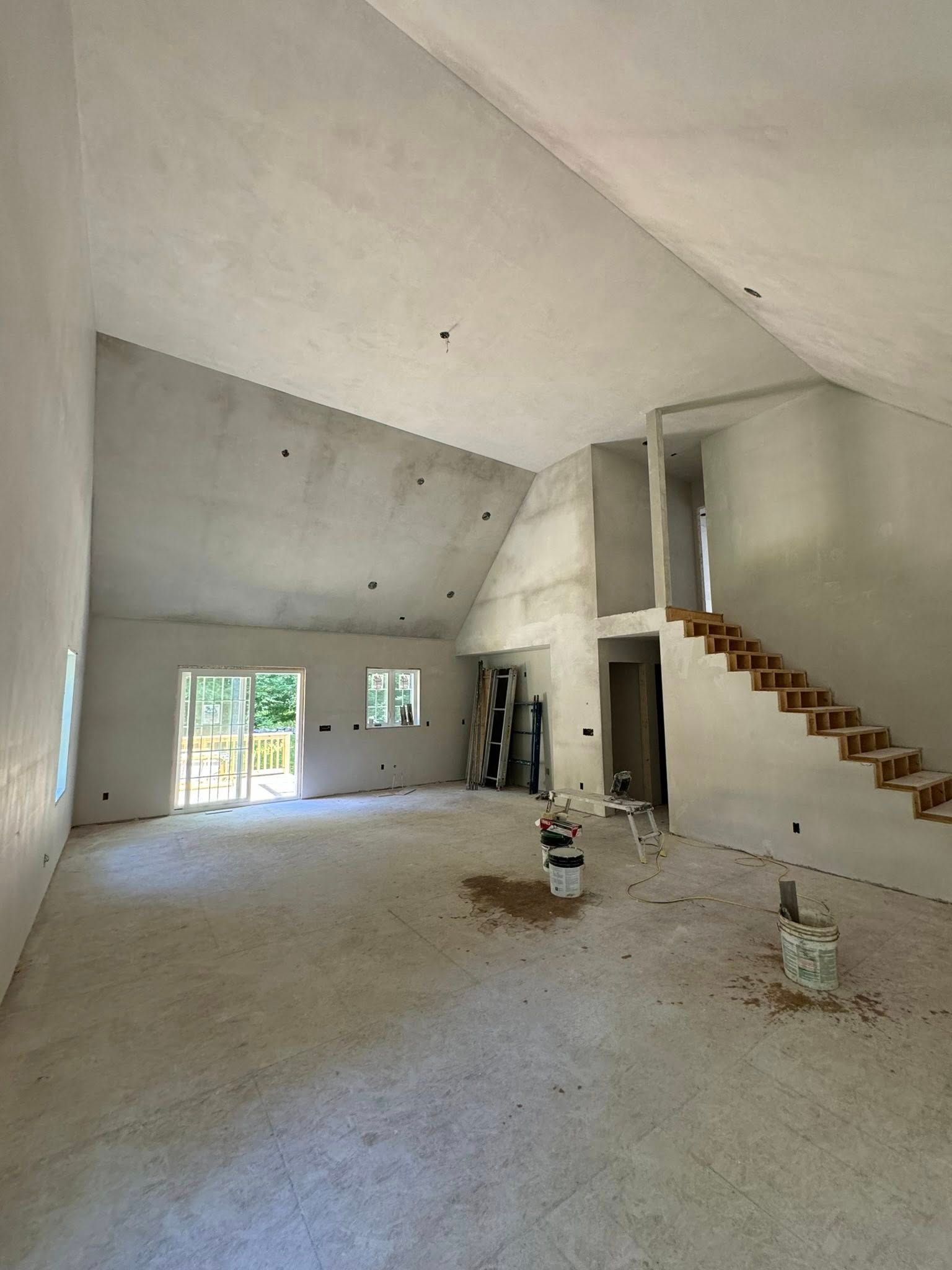 Interior of unfinished house, featuring high ceilings, stairs, and concrete walls. Interior of unfinished house, featuring high ceilings, stairs, and concrete walls.