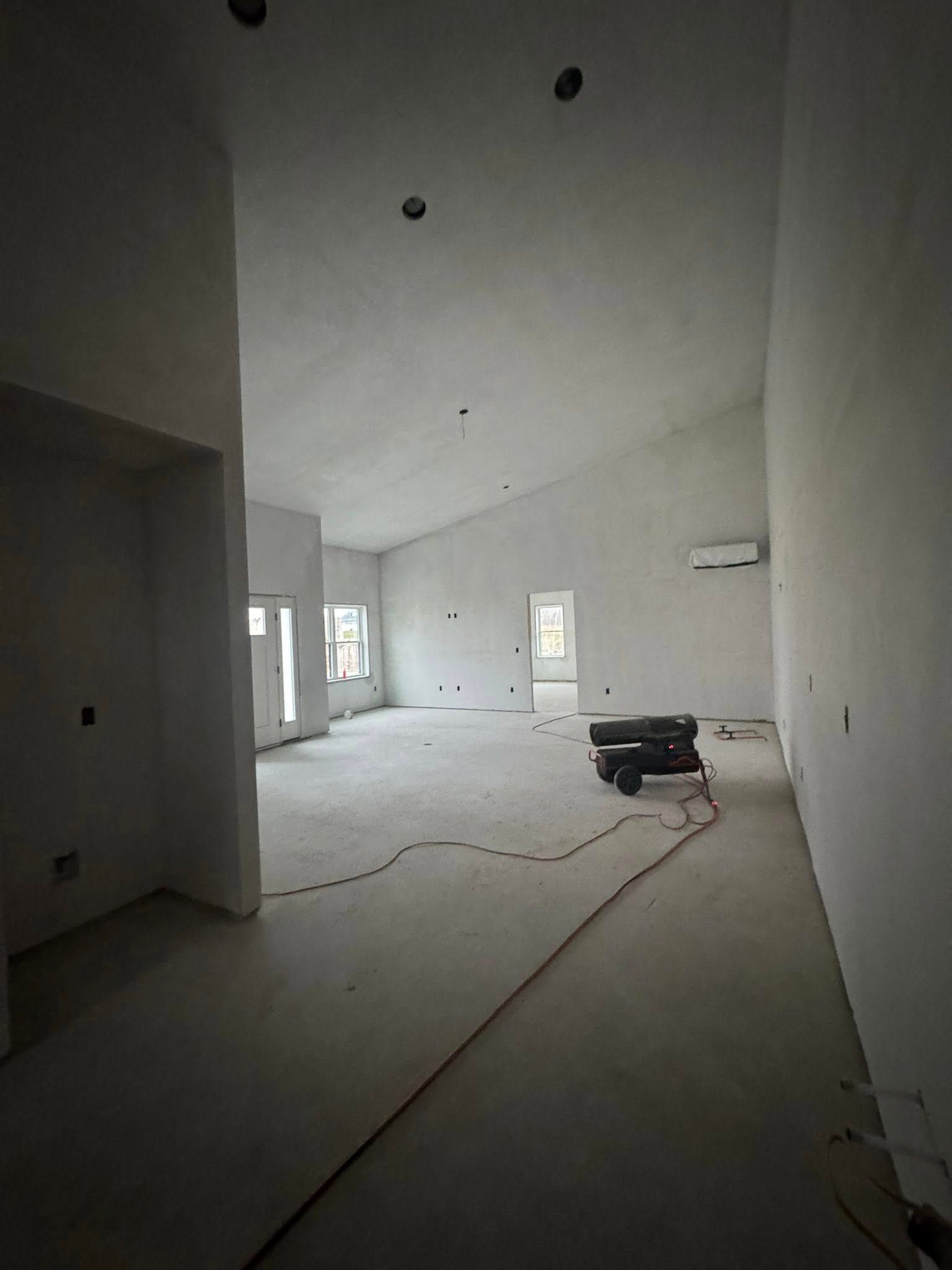 Interior of a room under construction with bare walls, sloped ceiling, and electrical wiring on the floor. Interior of a room under construction with bare walls, sloped ceiling, and electrical wiring on the floor.