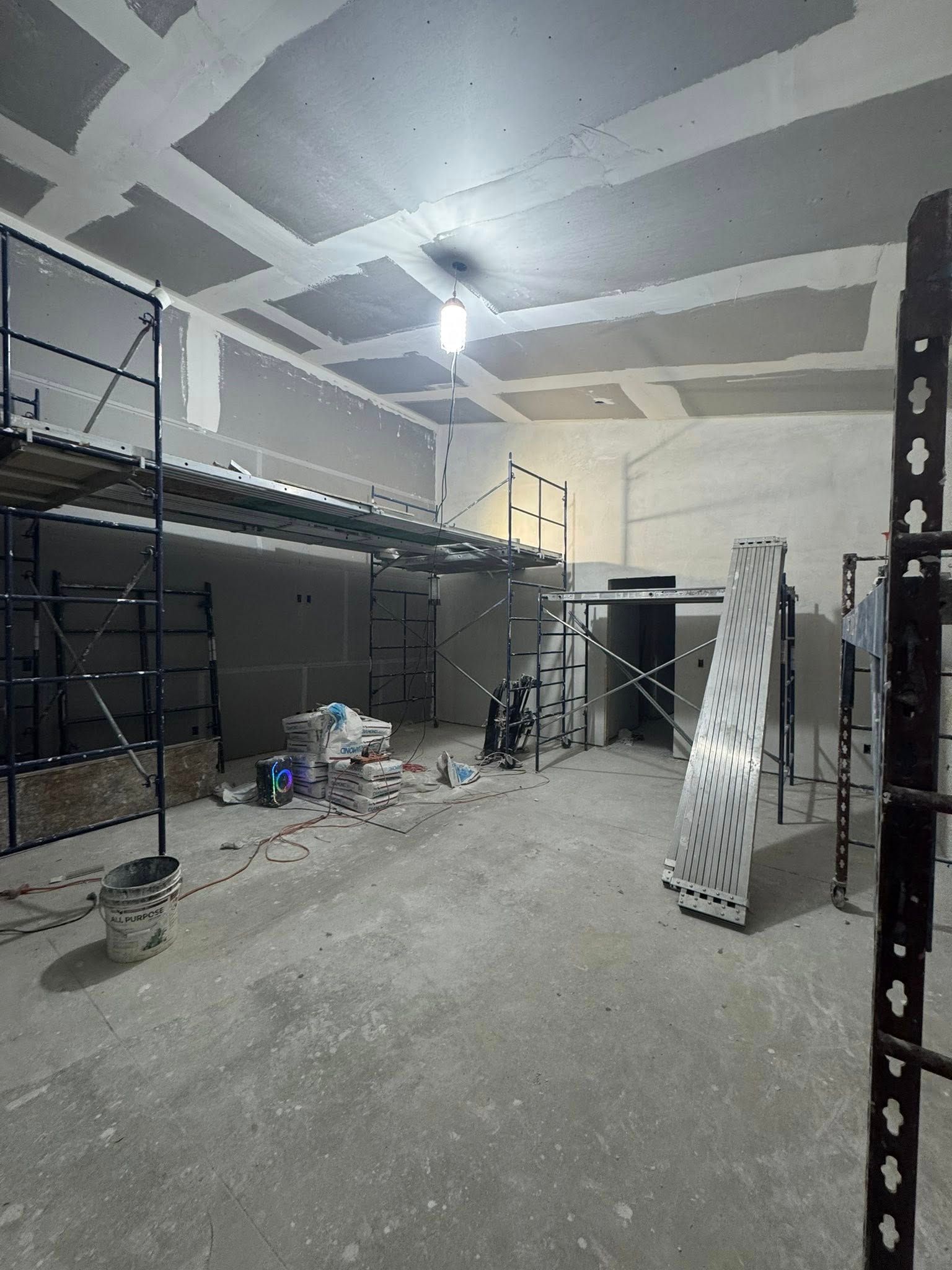 Interior construction site with scaffolding, drywall, and unfinished ceiling. Interior construction site with scaffolding, drywall, and unfinished ceiling.