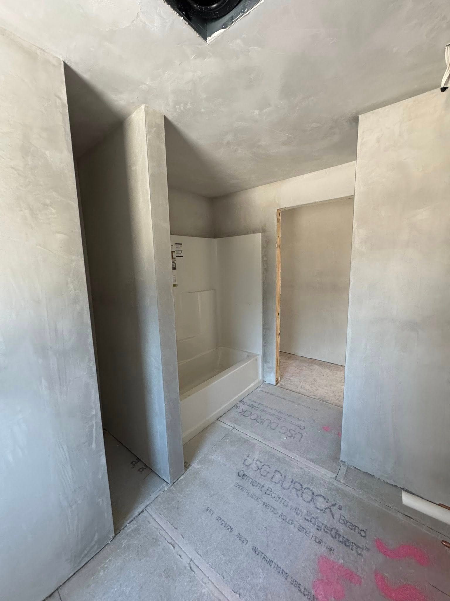 Bathroom under construction, cement walls and floor, shower stall visible. Bathroom under construction, cement walls and floor, shower stall visible.