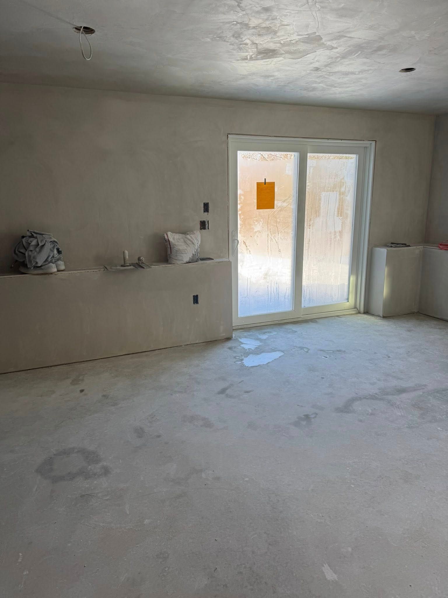 Interior room under construction with sliding glass door and unfinished walls.