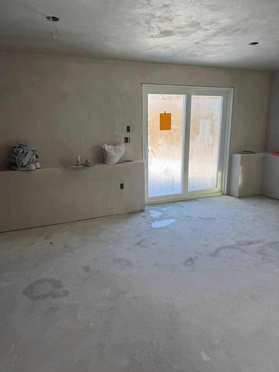 Interior room under construction with sliding glass door and unfinished walls.