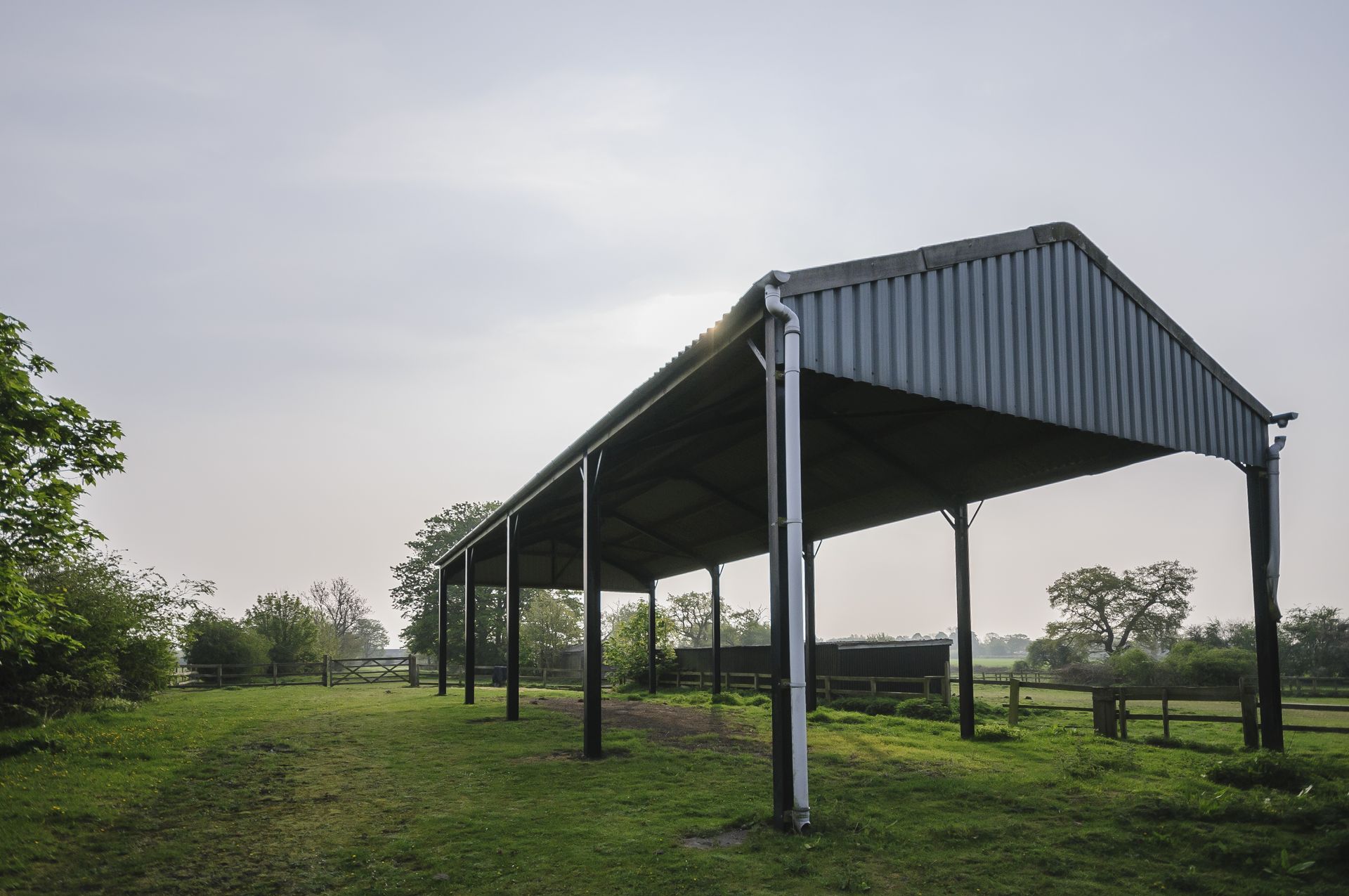 A large shed is sitting in the middle of a grassy field.