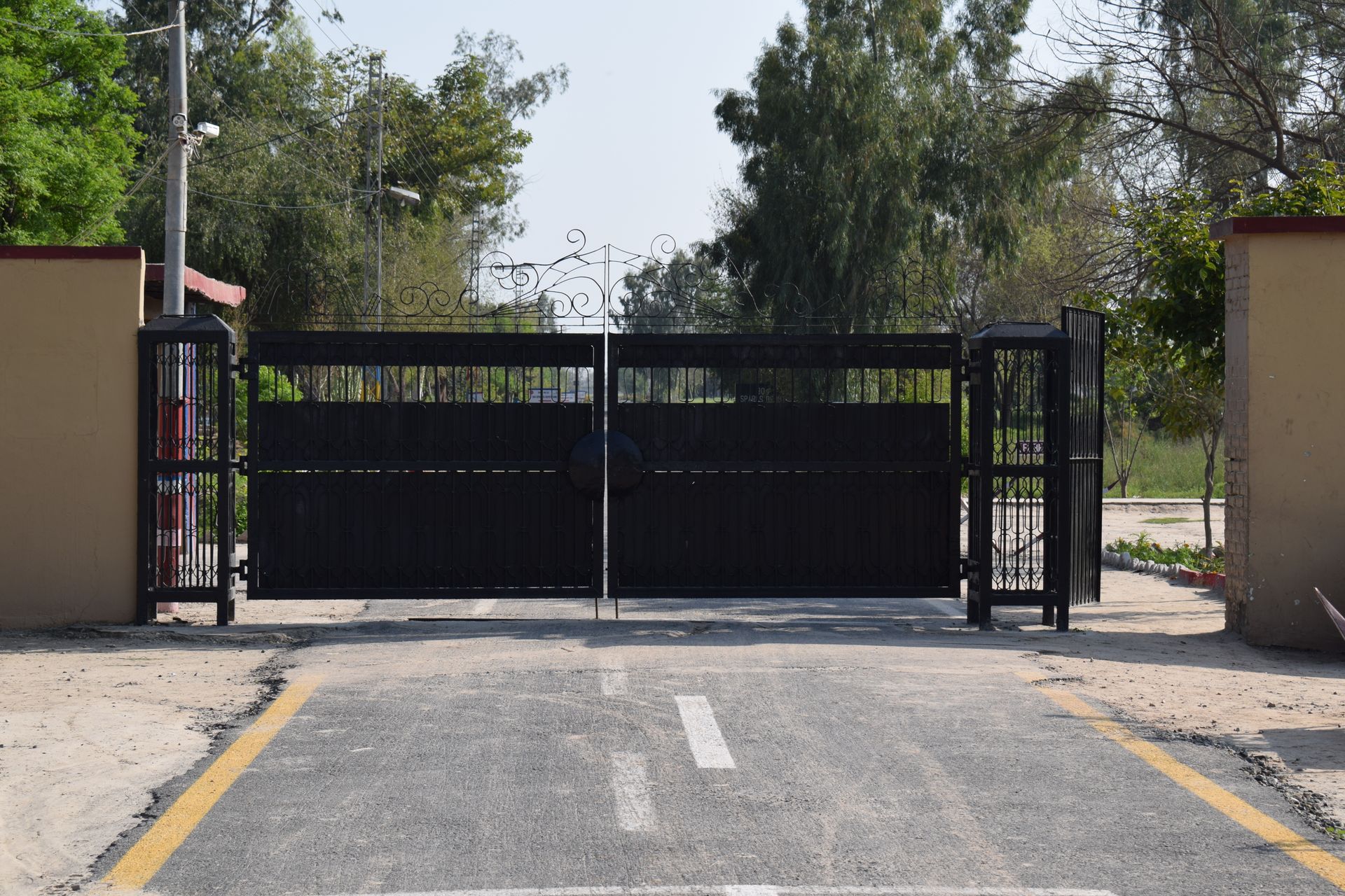 A black gate is open on the side of a road