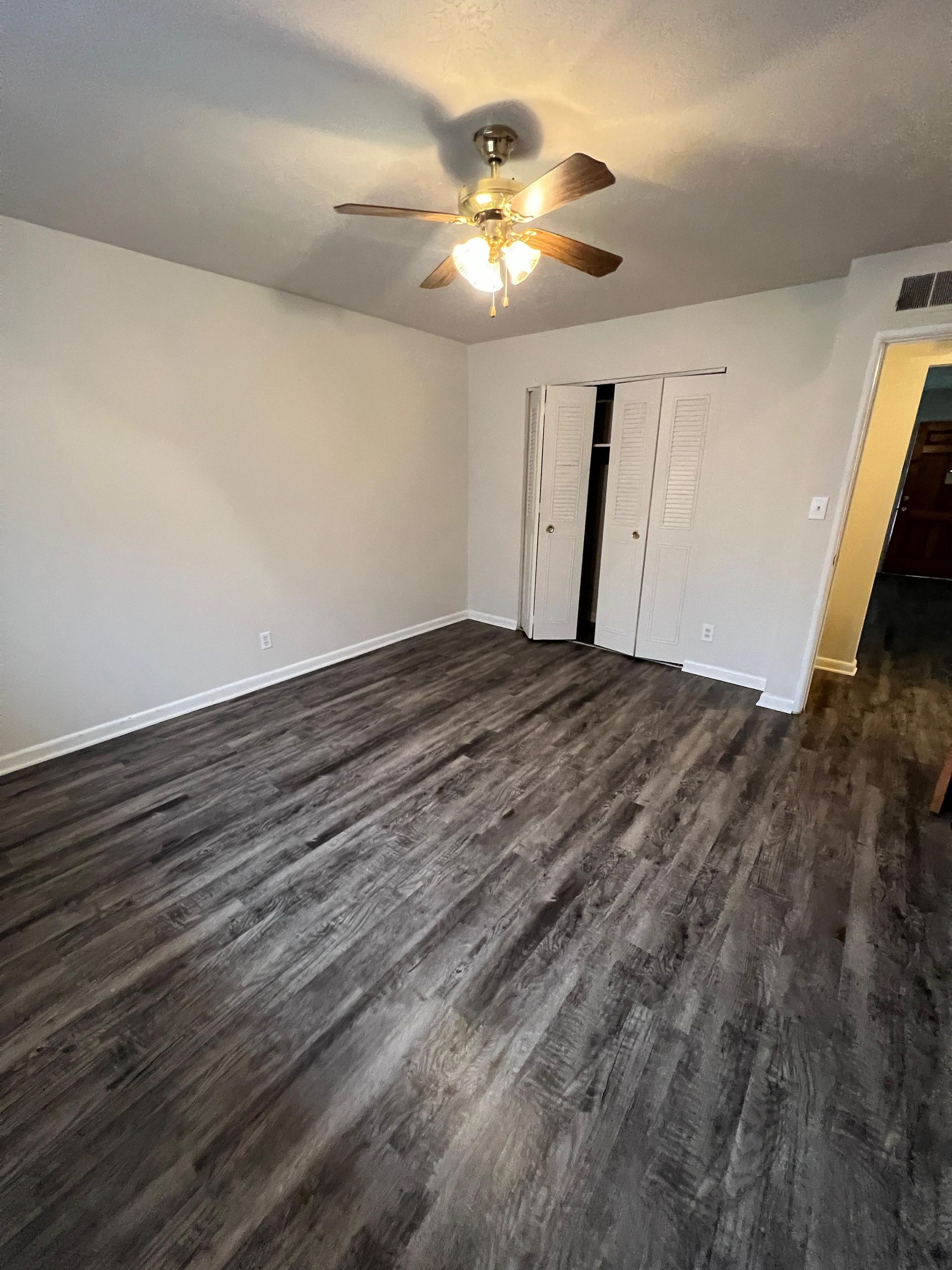 A bedroom with hardwood floors and a ceiling fan.