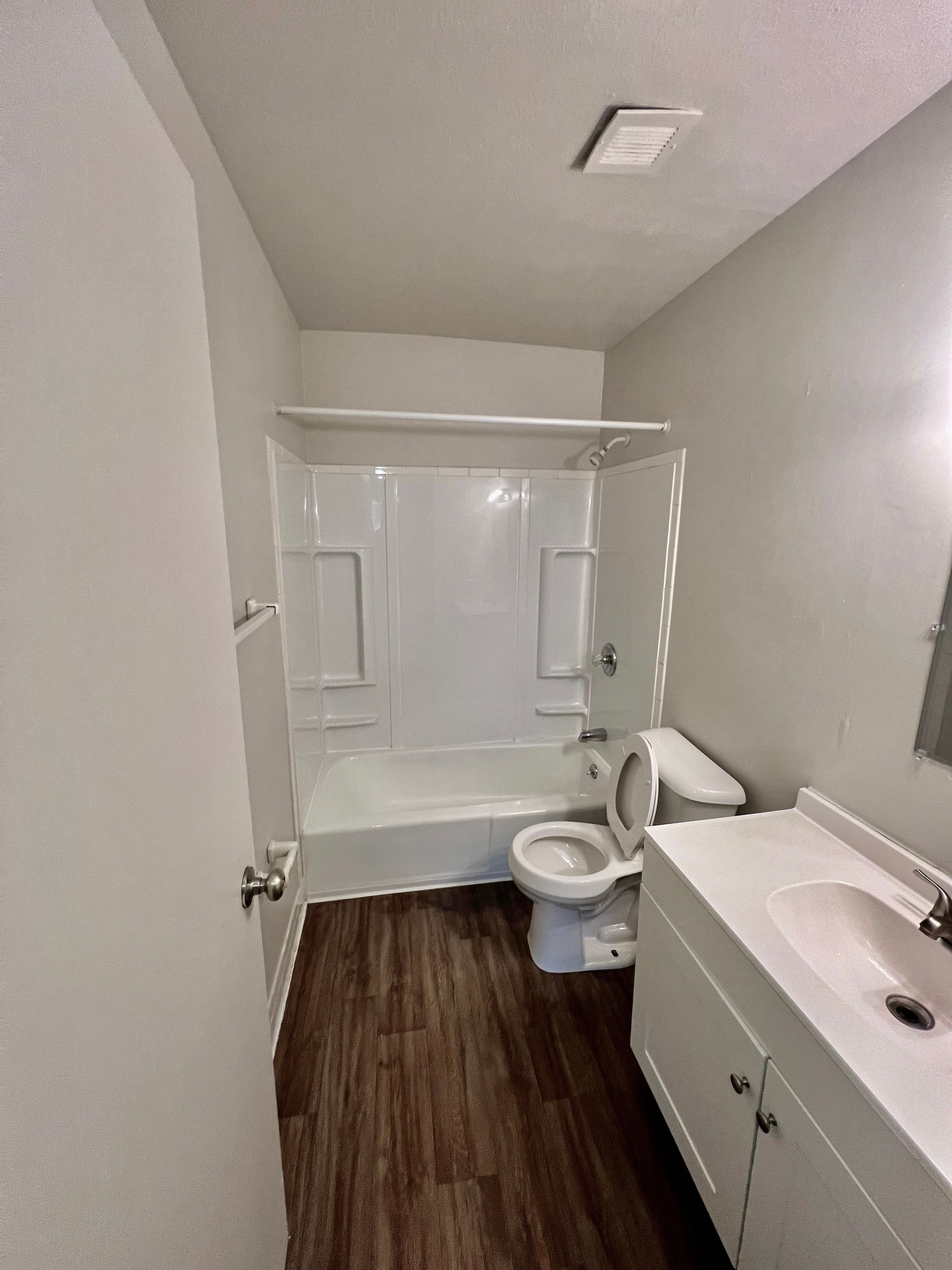 A bathroom with a tub , toilet , sink and mirror.
