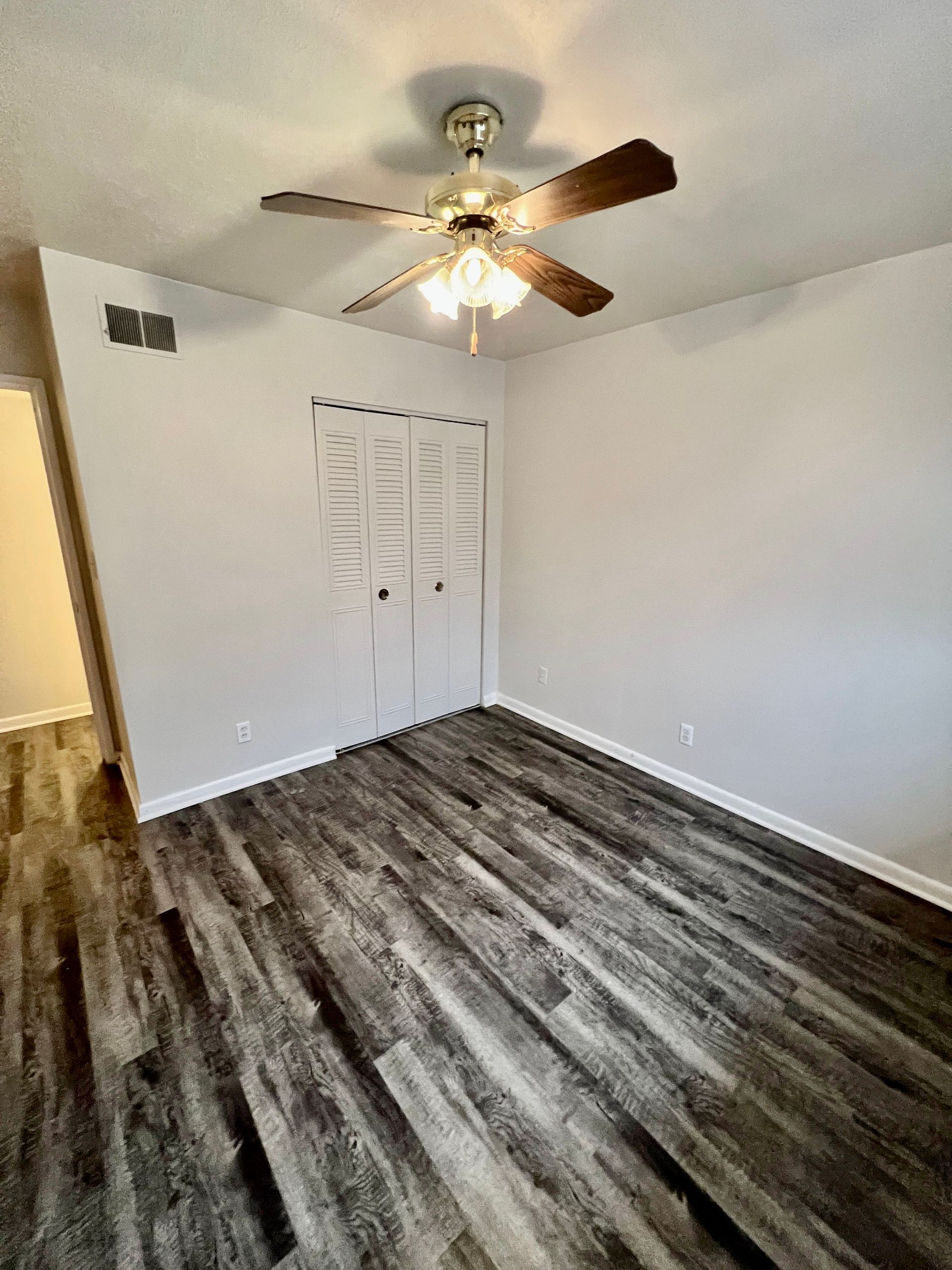 A bedroom with hardwood floors and a ceiling fan.