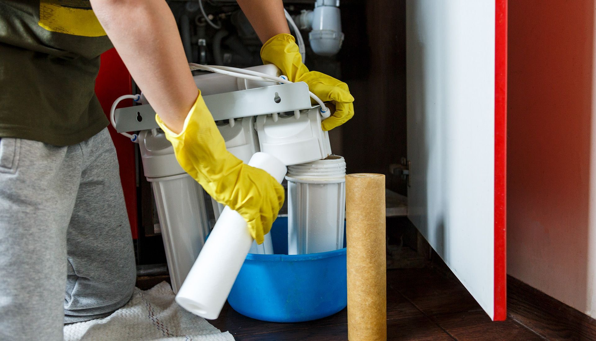 A person wearing yellow gloves is cleaning a water filter.