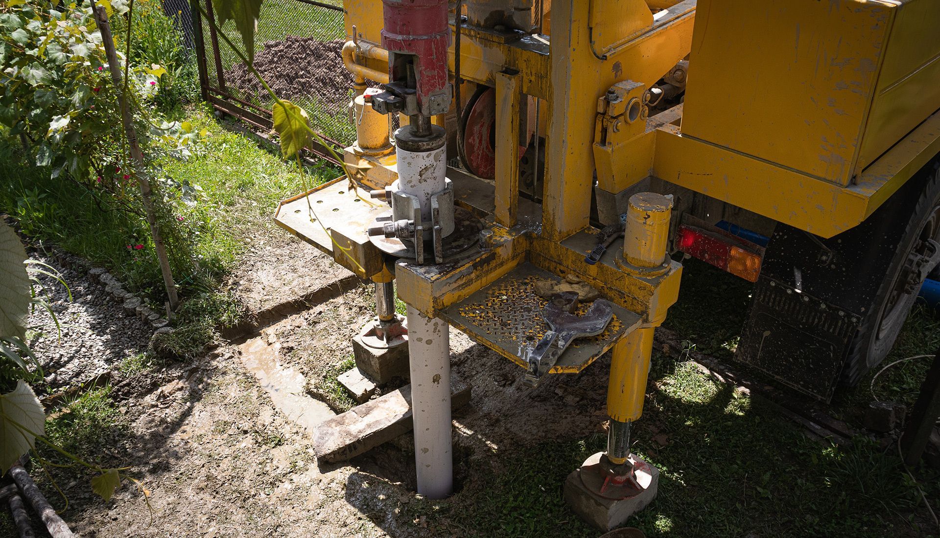 A yellow truck is drilling a hole in the ground.