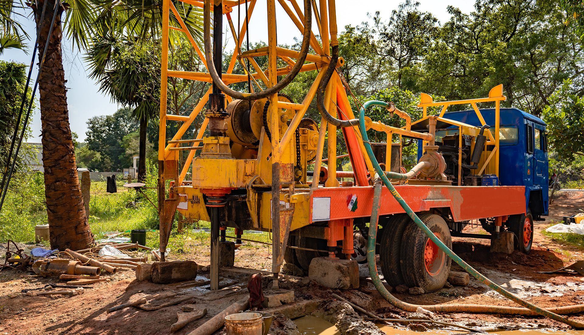 A yellow and orange truck is drilling a hole in the ground.