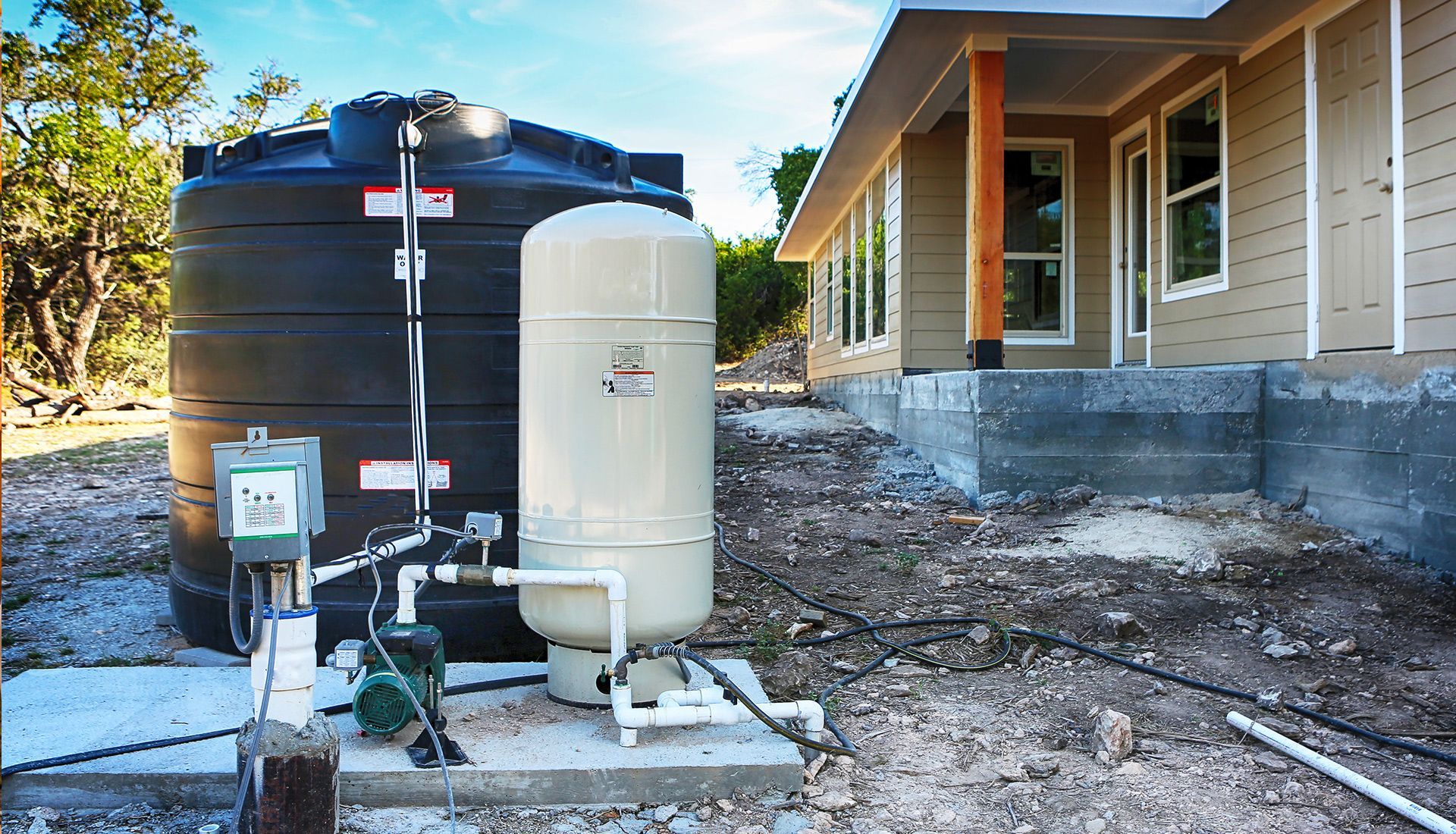 A water tank is sitting in front of a house under construction
