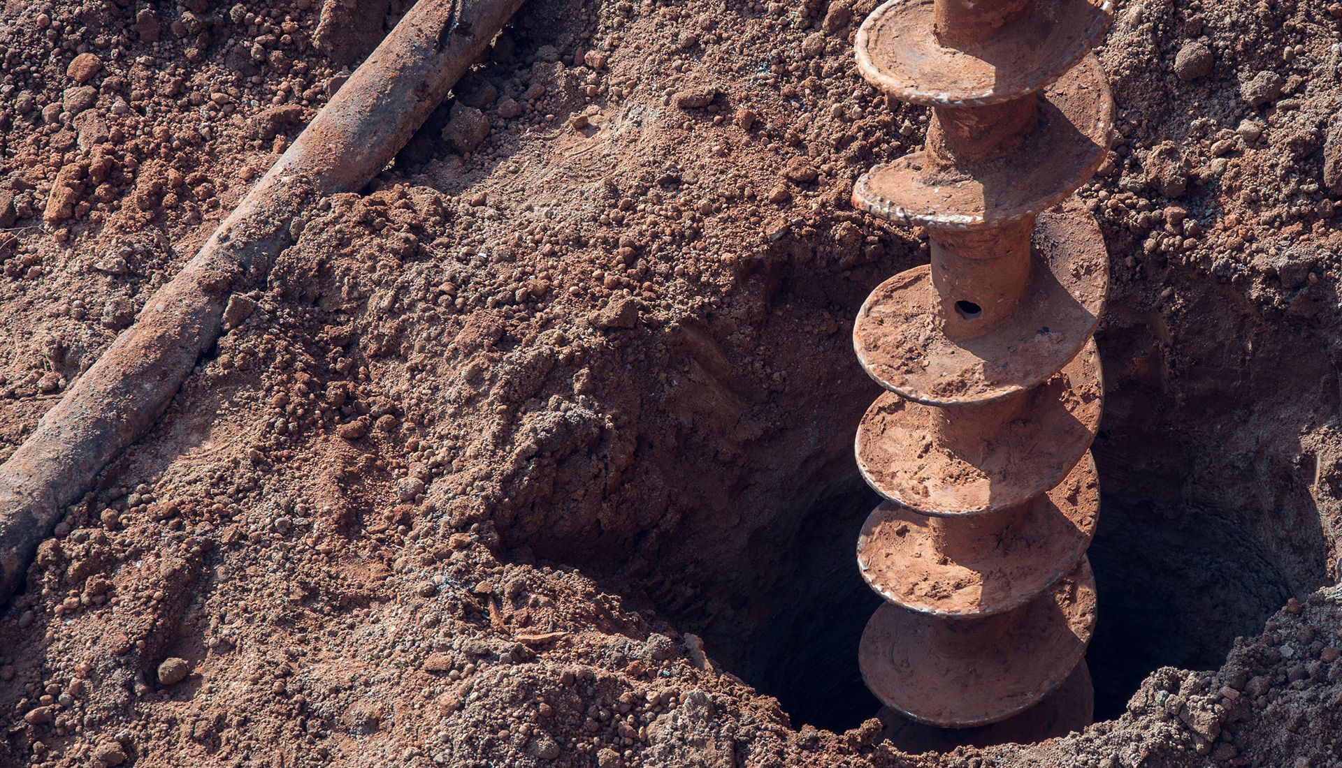 A hole in the ground with a drill bit in it