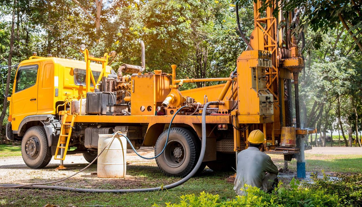 A man is sitting in front of a yellow truck.