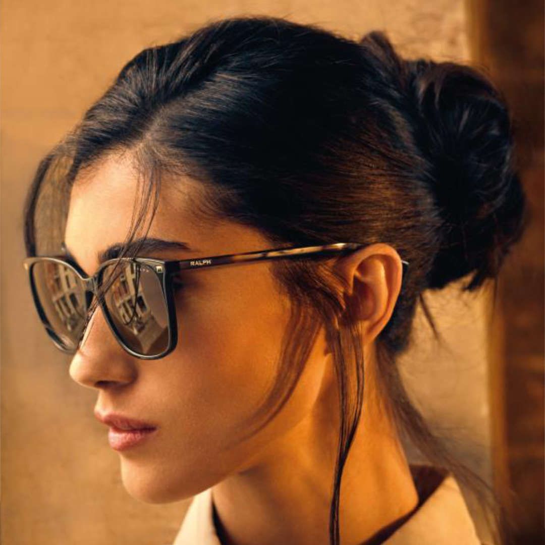 A woman wearing sunglasses has a bun in her hair