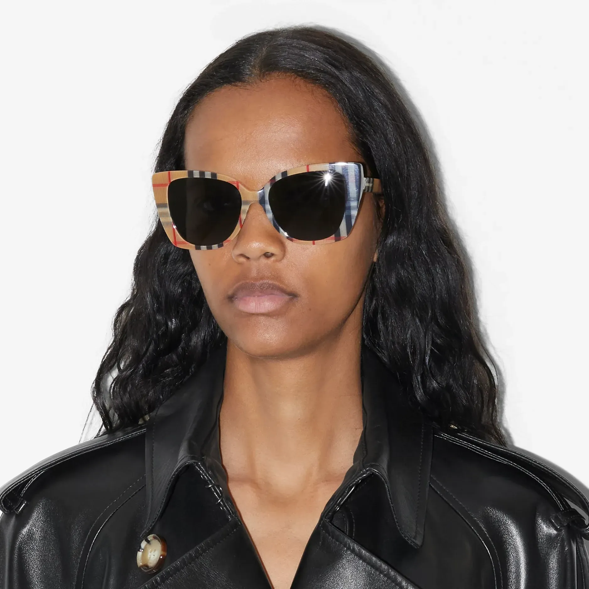 A woman wearing sunglasses and a black trench coat.