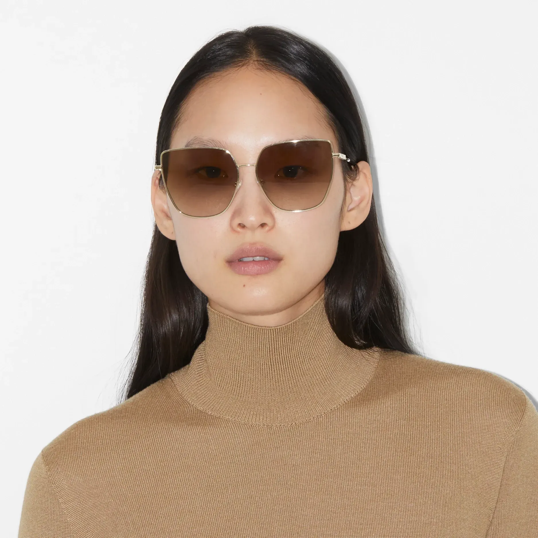 A woman wearing a tan sweater and sunglasses