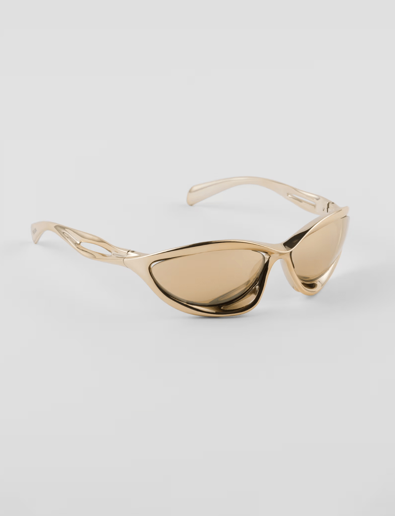 A pair of gold sunglasses are sitting on a white surface.