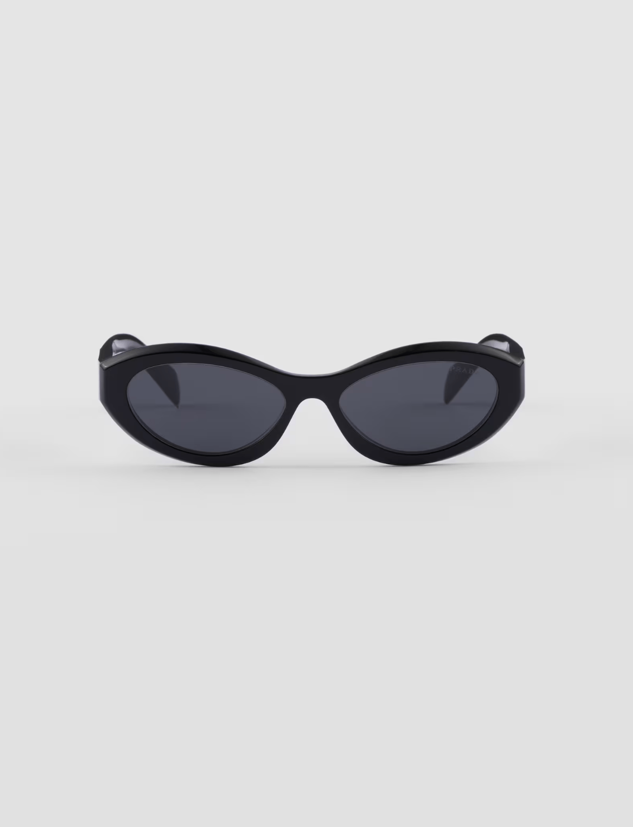 A pair of black sunglasses are sitting on a white surface.