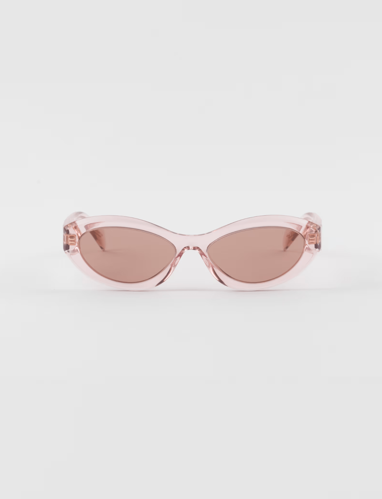 A pair of pink sunglasses with a clear frame and brown lenses on a white surface.
