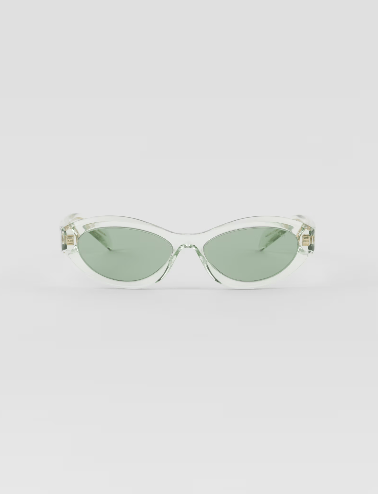 A pair of clear sunglasses with green lenses on a white background.