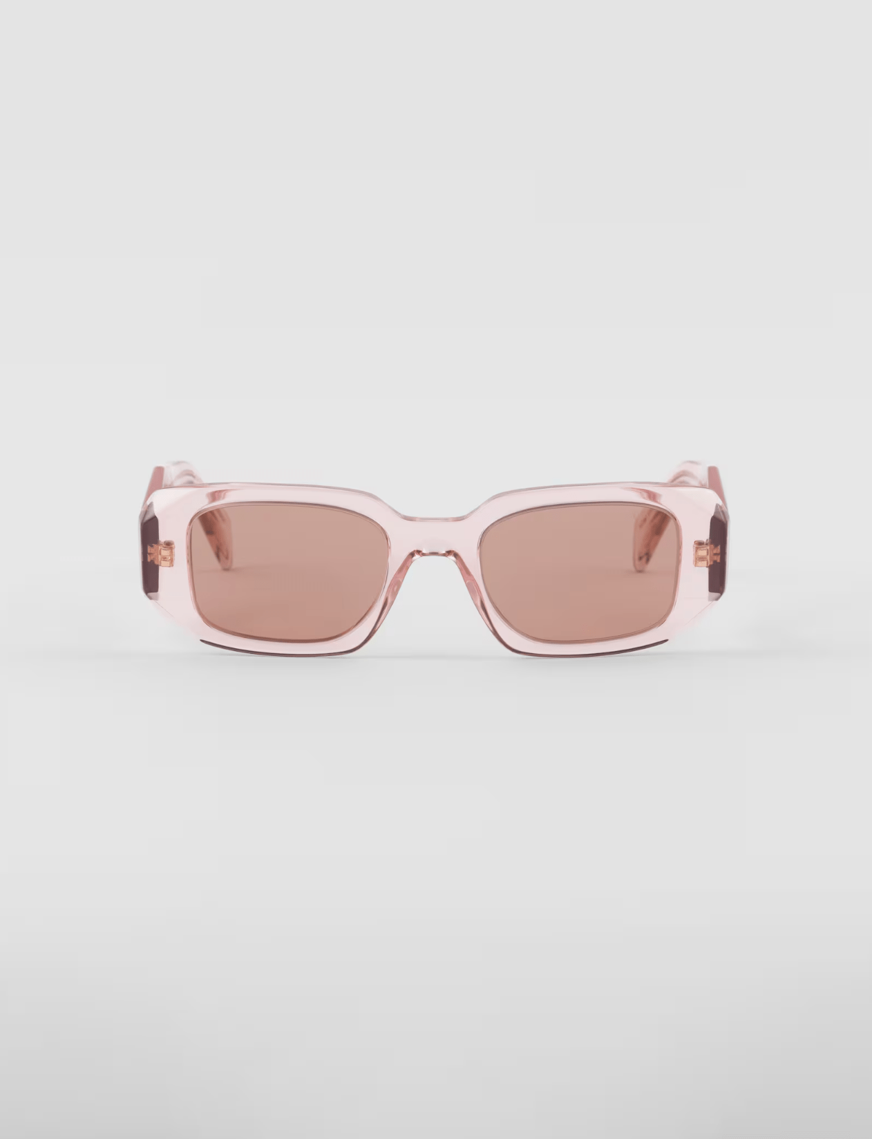 A pair of pink sunglasses with brown lenses on a white surface.