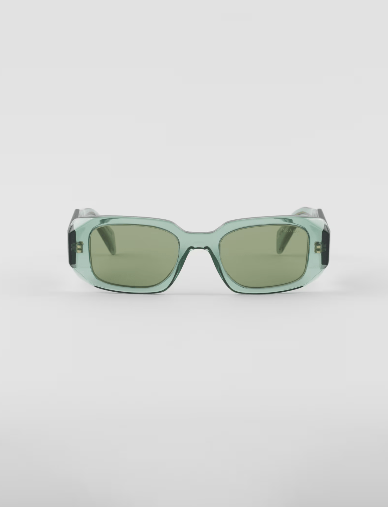 A pair of green sunglasses are sitting on a white surface.